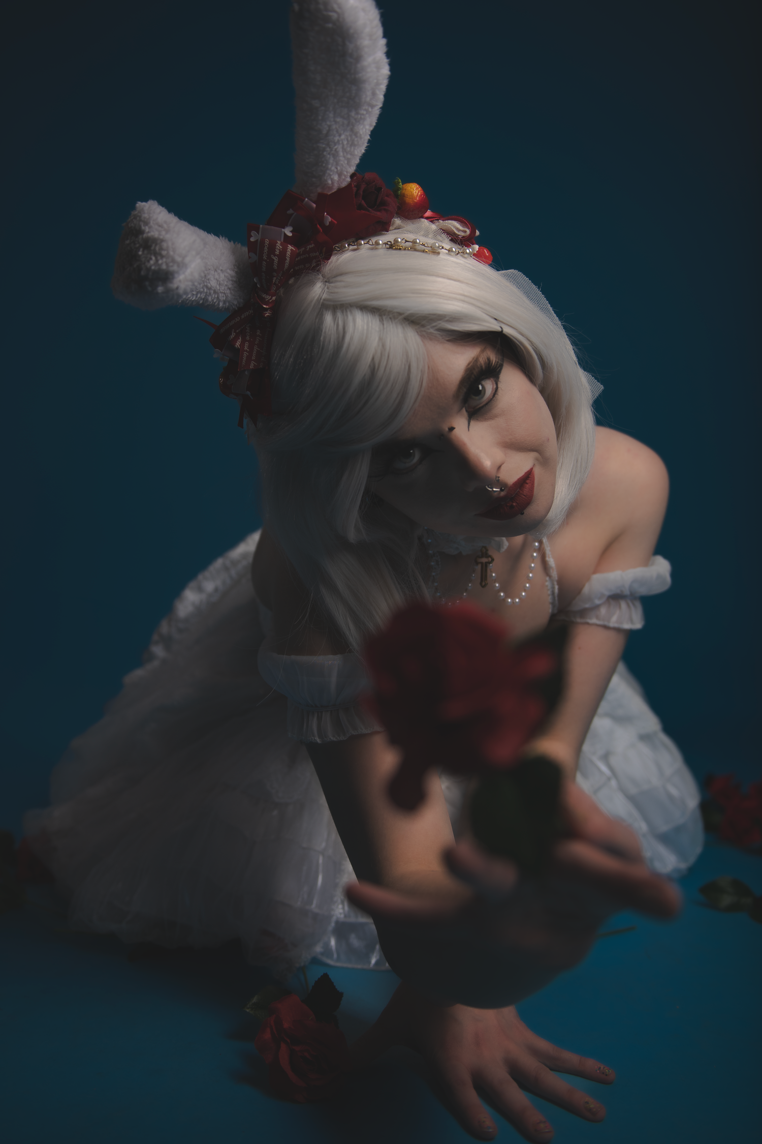 Artistic photoshoot featuring dramatic lighting against dark blue background with gothic fantasy styled elements.