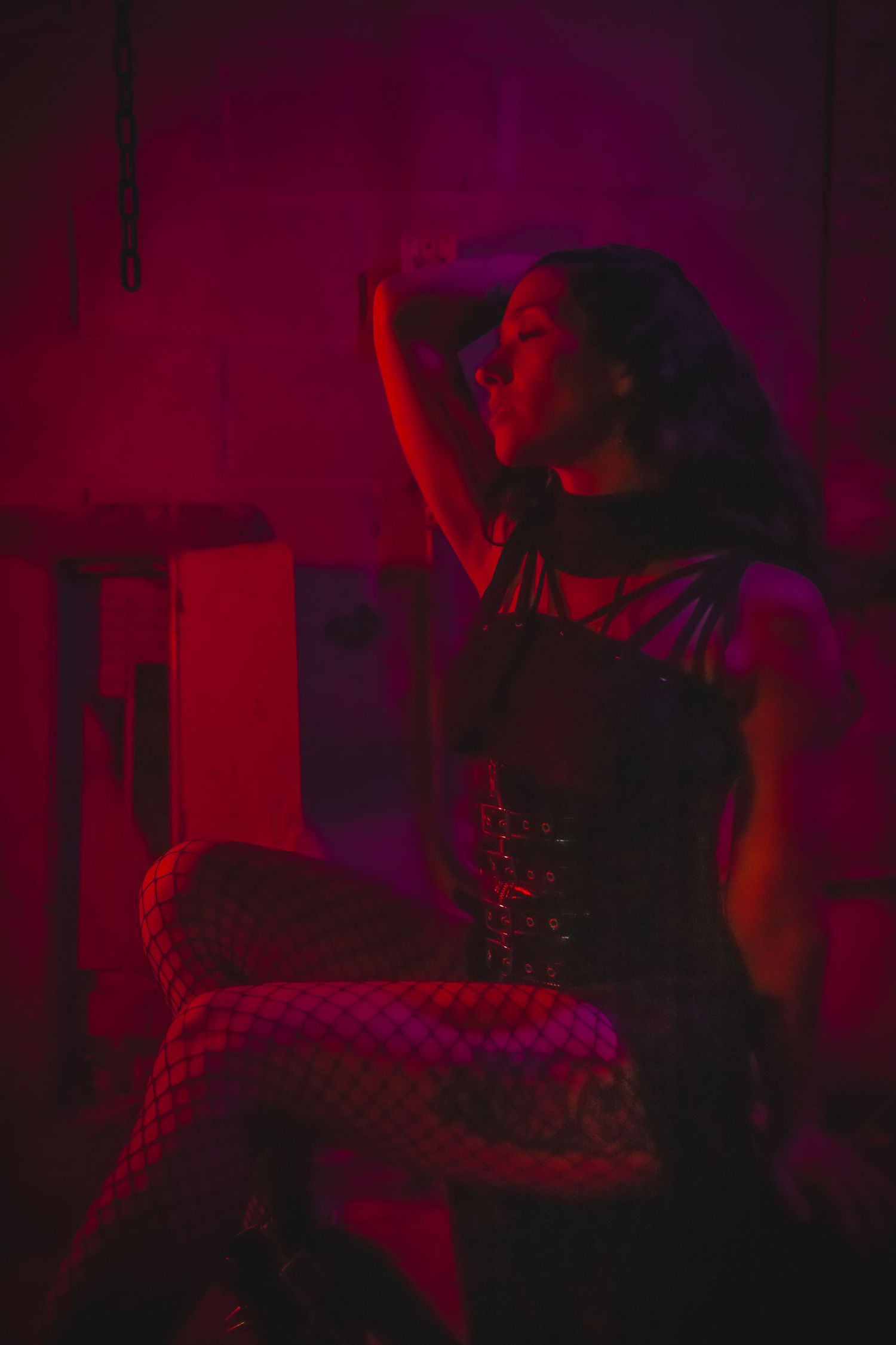 Figures create dramatic shadows against a backdrop of intense red theatrical lighting in a dark space.