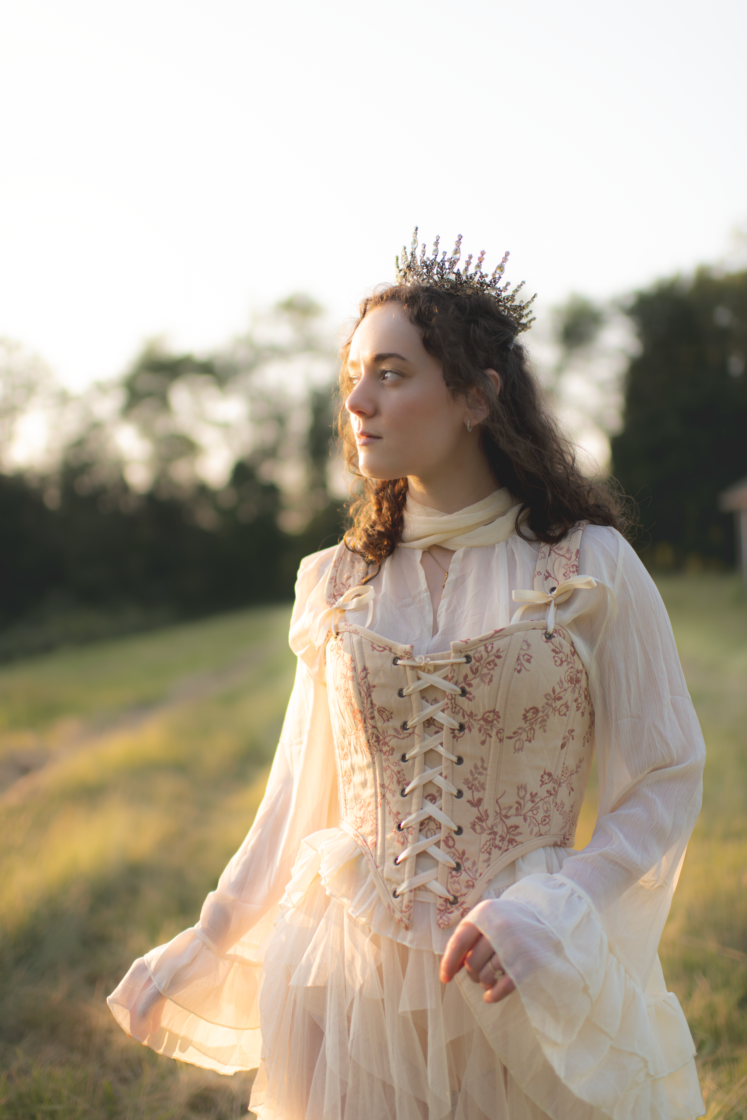A person in a vintage-style cream dress with lace details twirls in a sunlit meadow during golden hour.