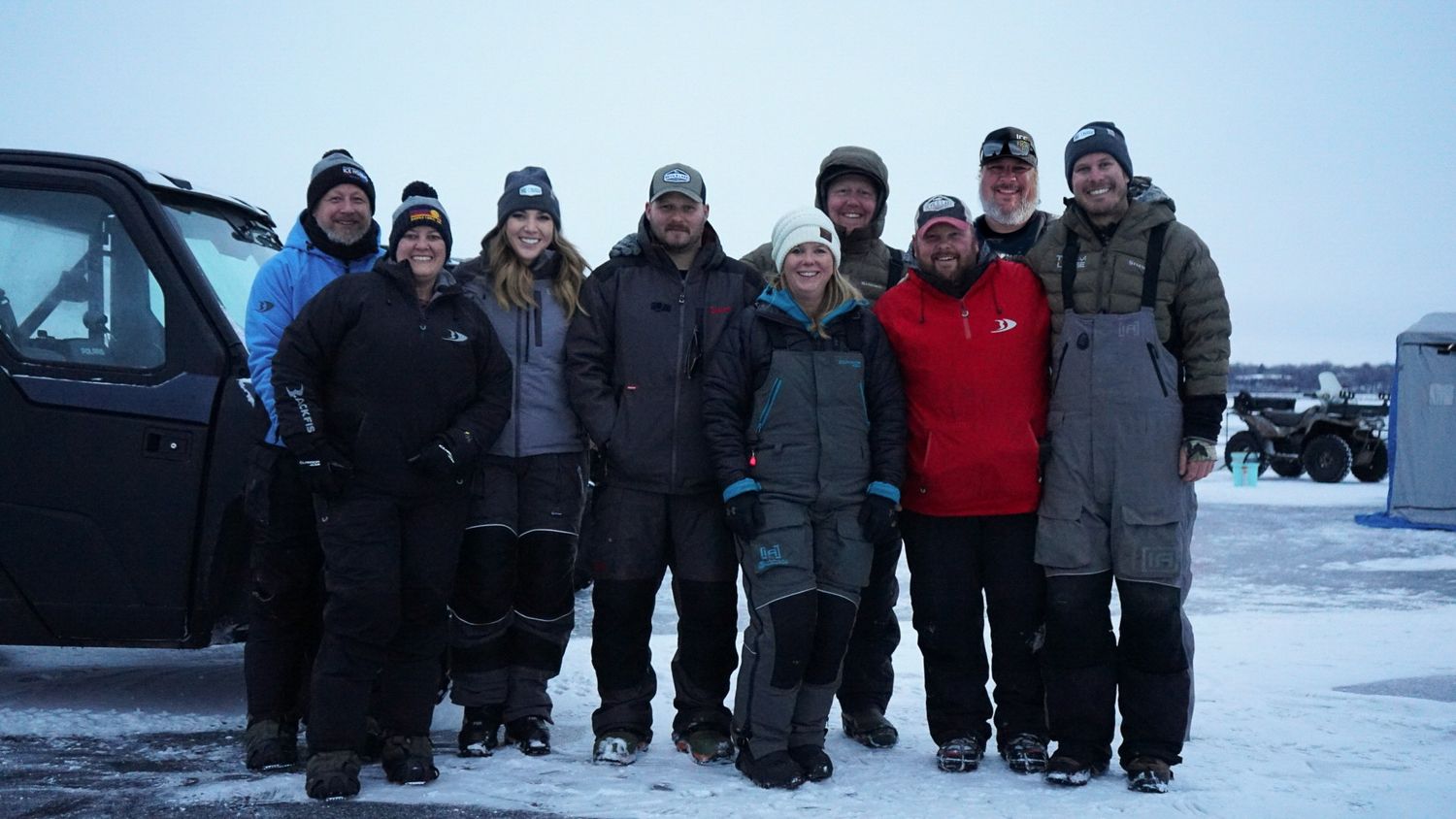 Group of winter anglers gathered on frozen lake for ice fishing expedition.