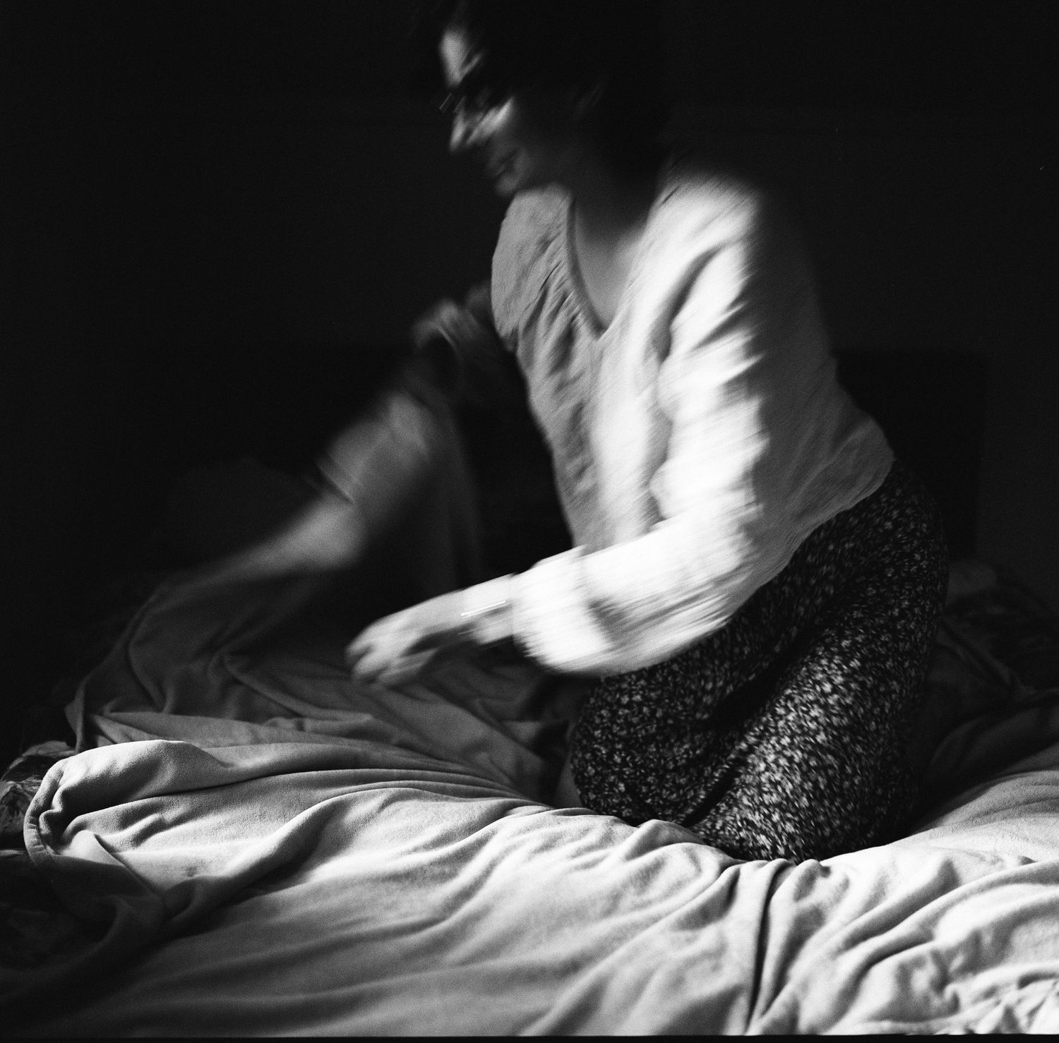 Black and white photo of a woman on a bed in soft light