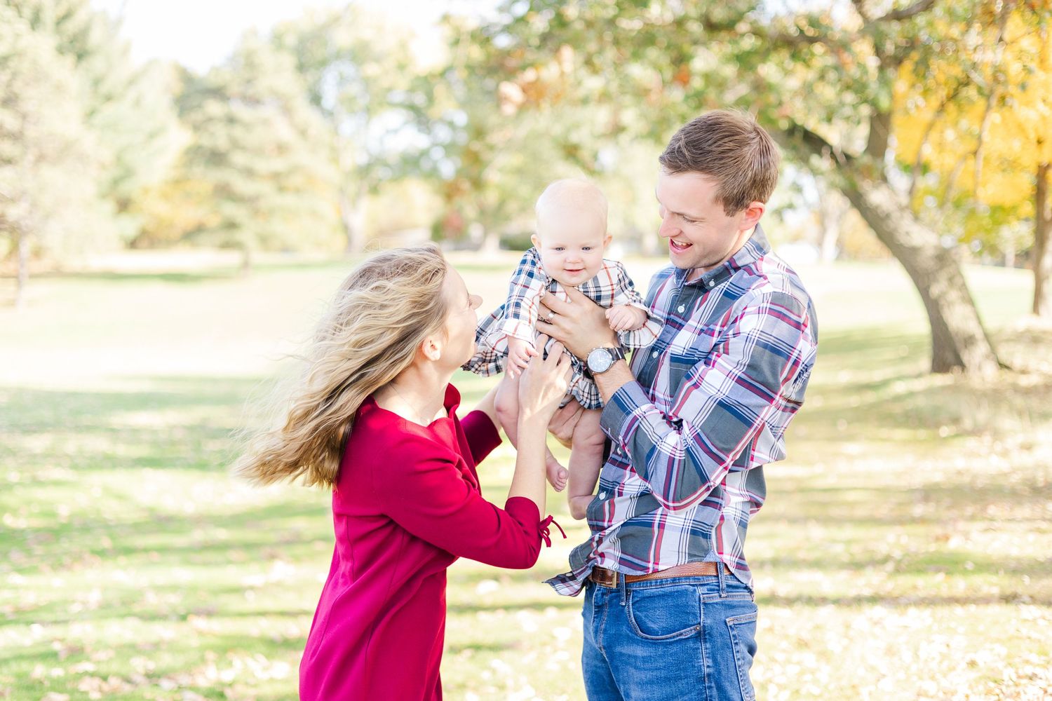 Family playing and embracing in autumn park with golden leaves.