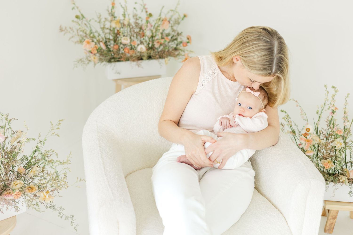 Bright airy indoor photography session with floral arrangements and white decor.