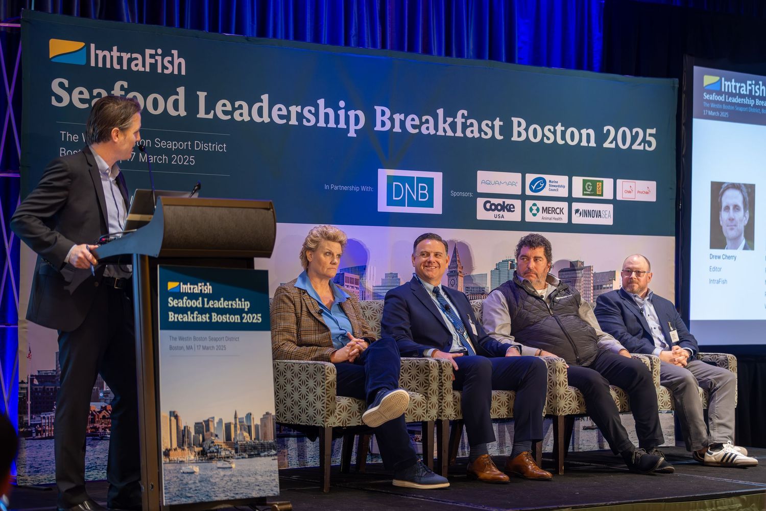 Business conference panel discussion with speakers seated on stage at Seafood Leadership Breakfast Boston 2025 event.