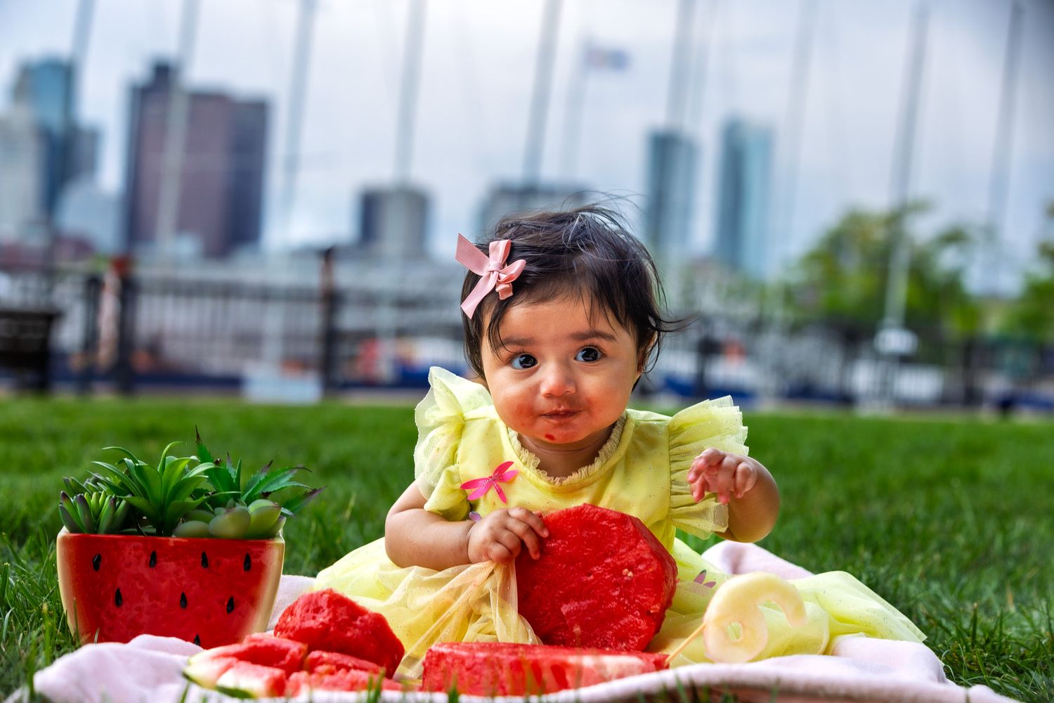 A child enjoying fresh watermelon outdoors on a sunny summer day with an urban backdrop.