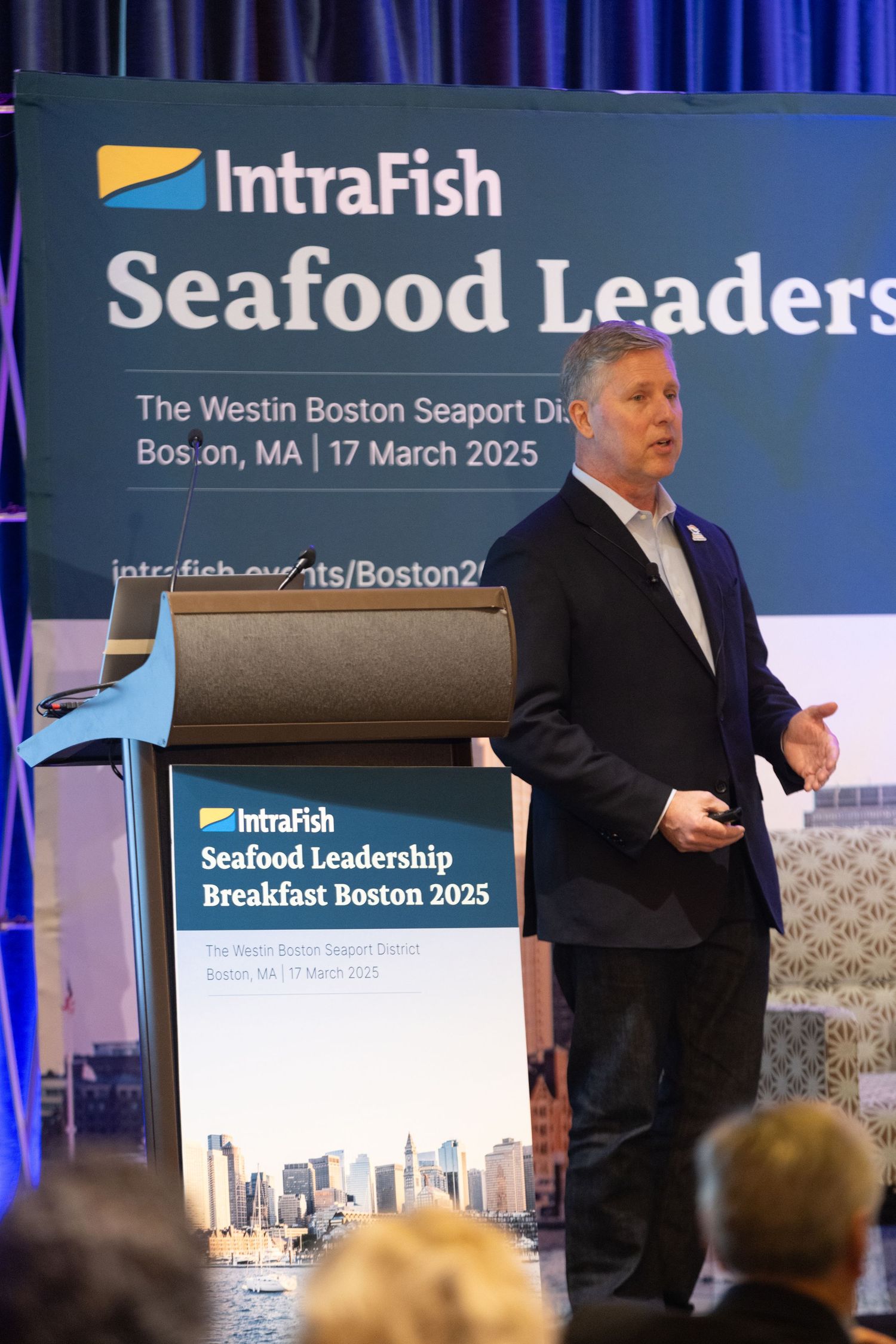 Business conference presentation at the IntraFish Seafood Leadership Breakfast in Boston with speaker on stage.
