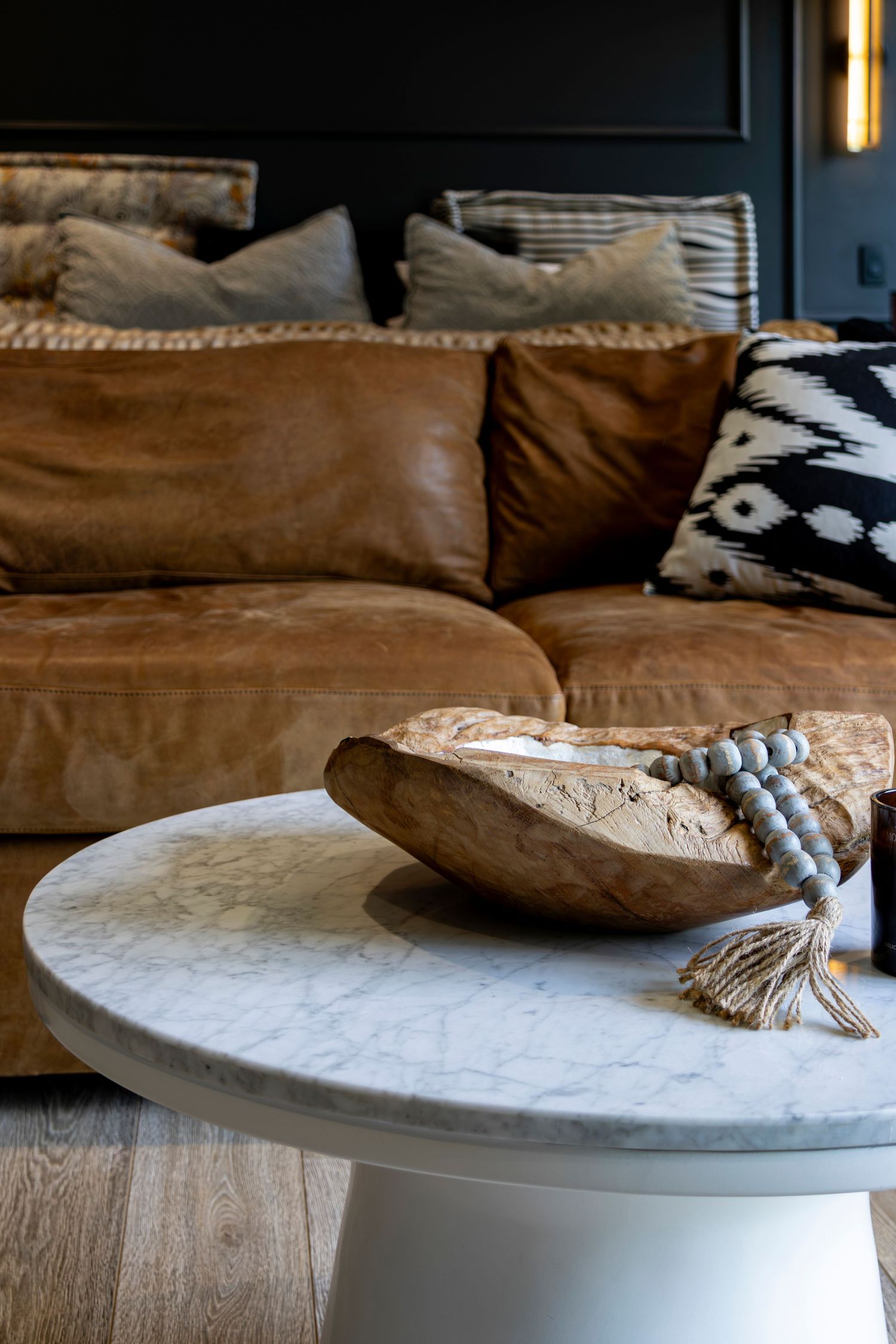 White circular coffee table with brown decorative pillows against a dark background.
