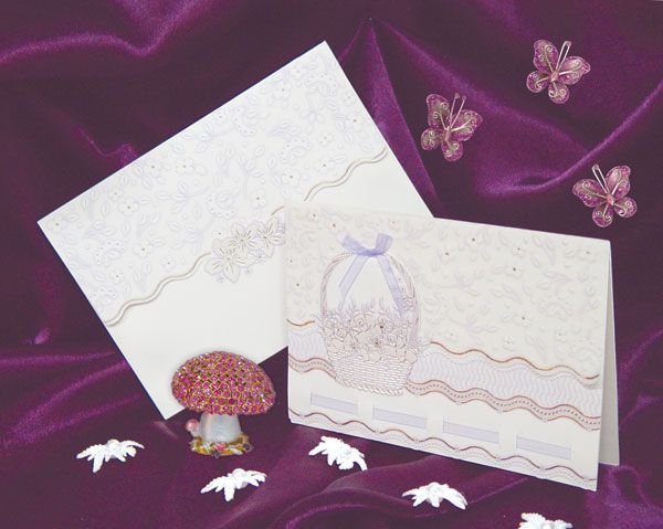 Wedding invitation cards with delicate lace patterns and butterfly decorations on purple velvet.