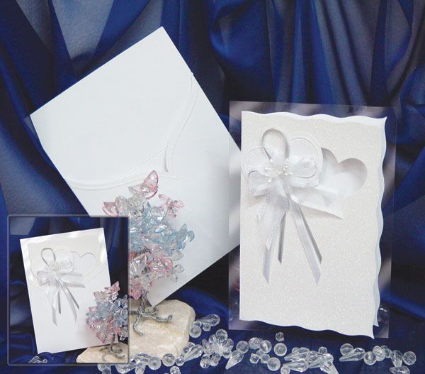Three white wedding invitation cards with floral designs and ribbons against a blue fabric backdrop.