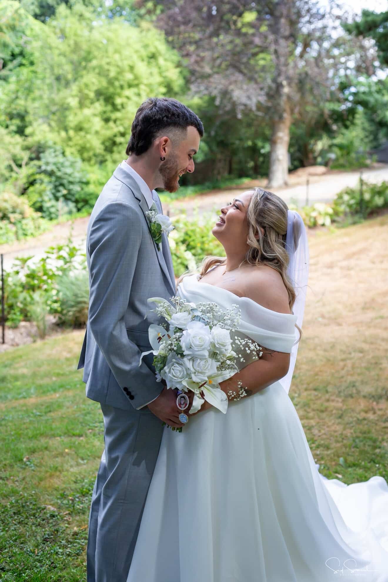 Long blonde thick hair with clip in extensions with glamorous Hollywood style waves and a high half up half down pony bride is wearing a vei