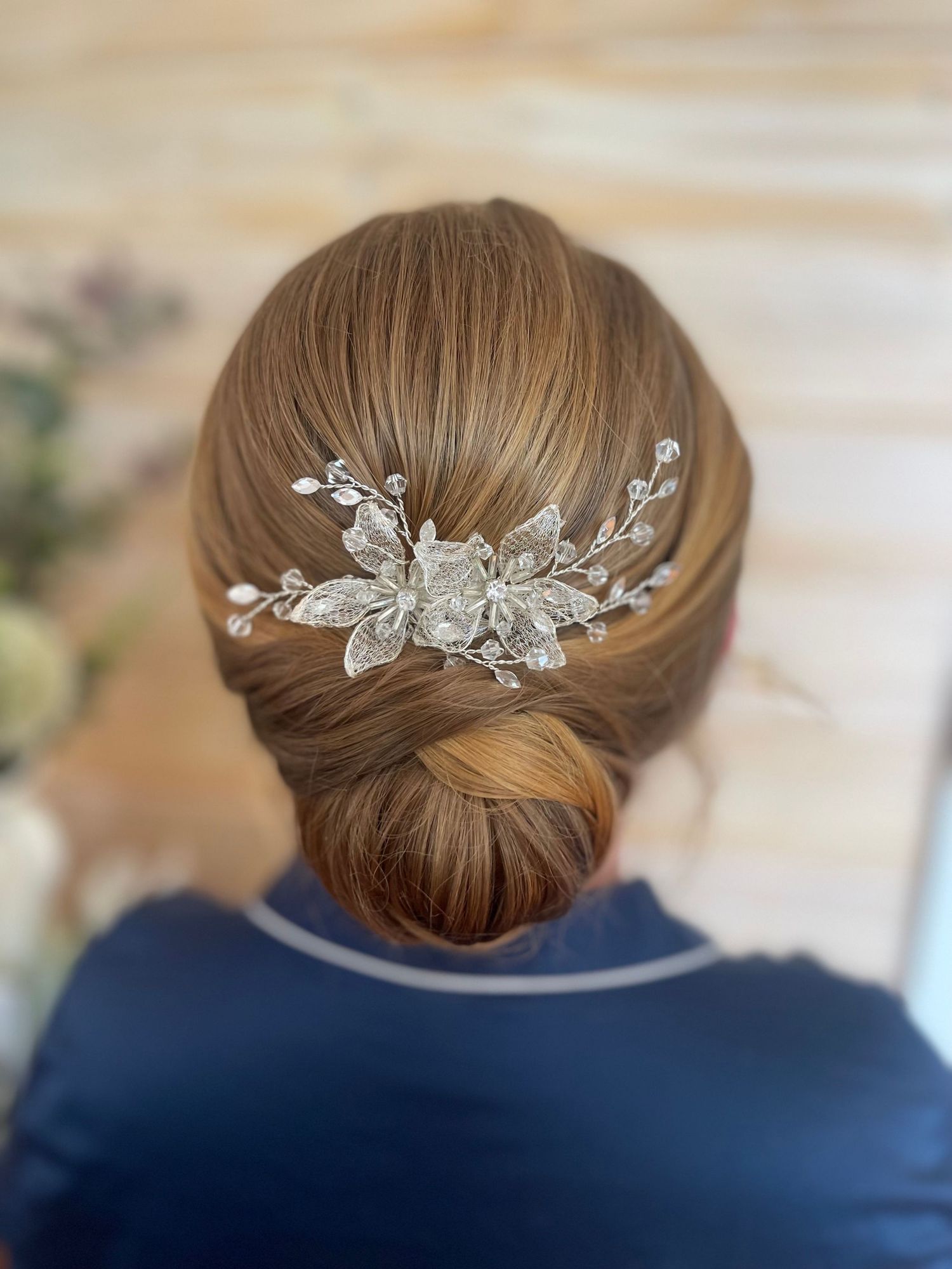 Elegant slicked back low bun on medium length hair detailed with diamond floral hair accessorie