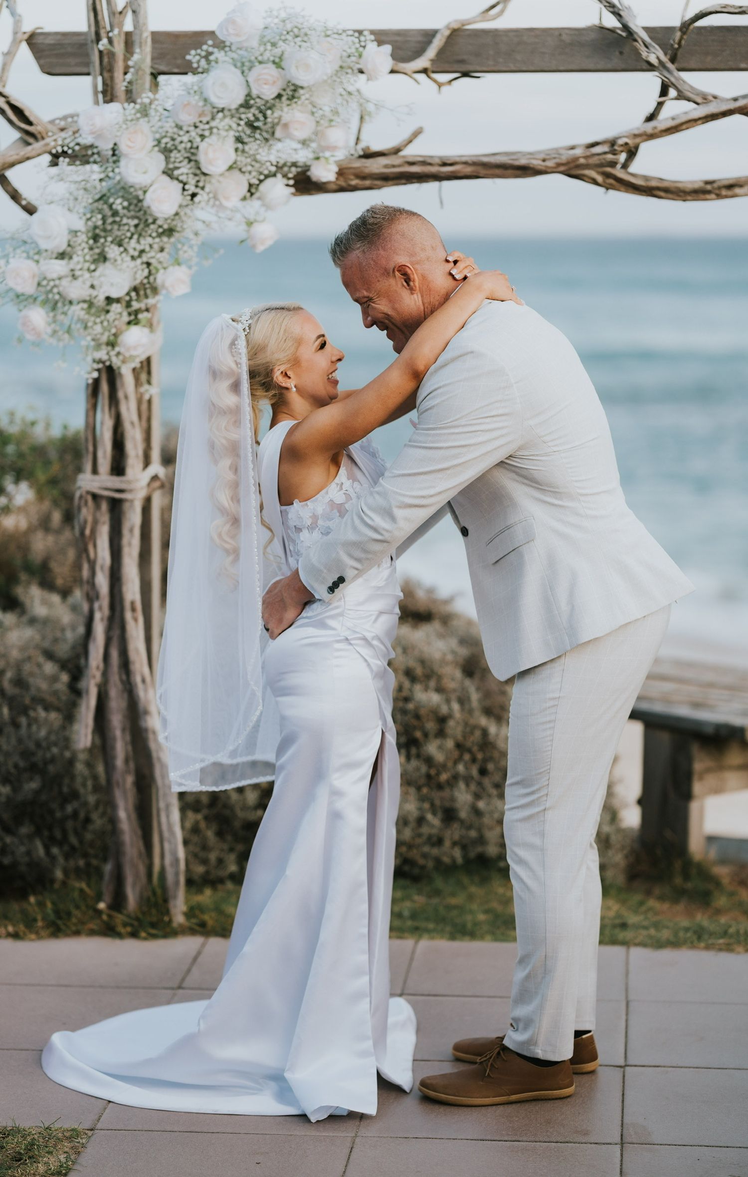 Bride with very fine long blonde hair wearing clip in extensions and her hair is in a glam Hollywood wave high pony tail with veil on beach