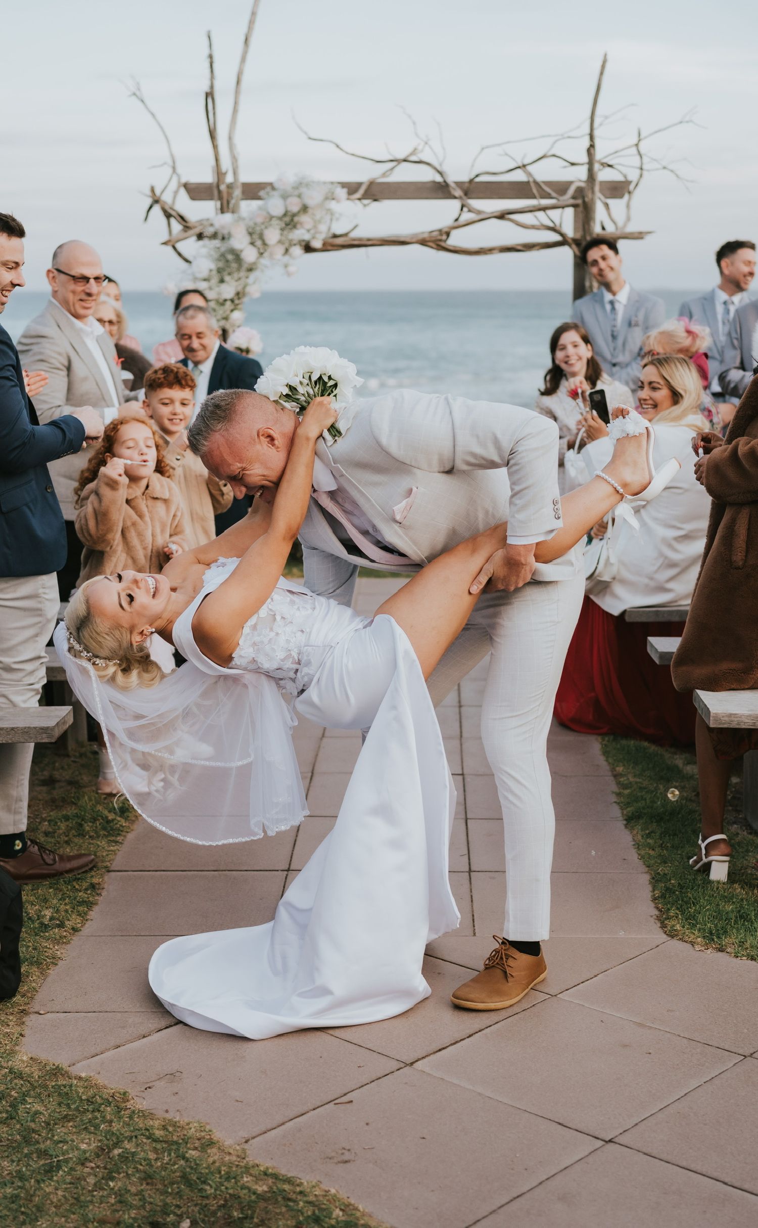 Beach wedding. Elegant bridal pony tail styled in glam Hollywood waves long blonde thick hair wearing a veil. Bride is wearing extensions