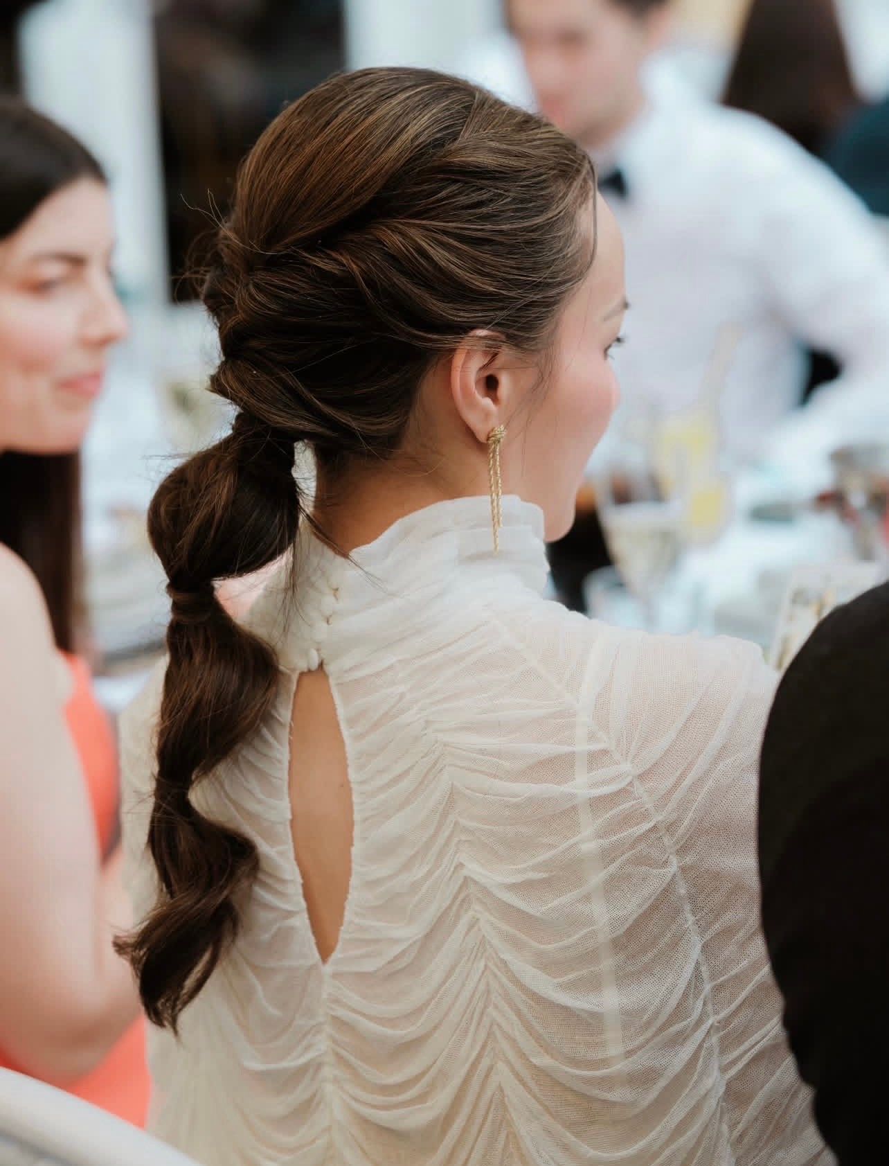 Long brunette hair twisted and plaited into a bubbled pony tail for a boho glam look.
