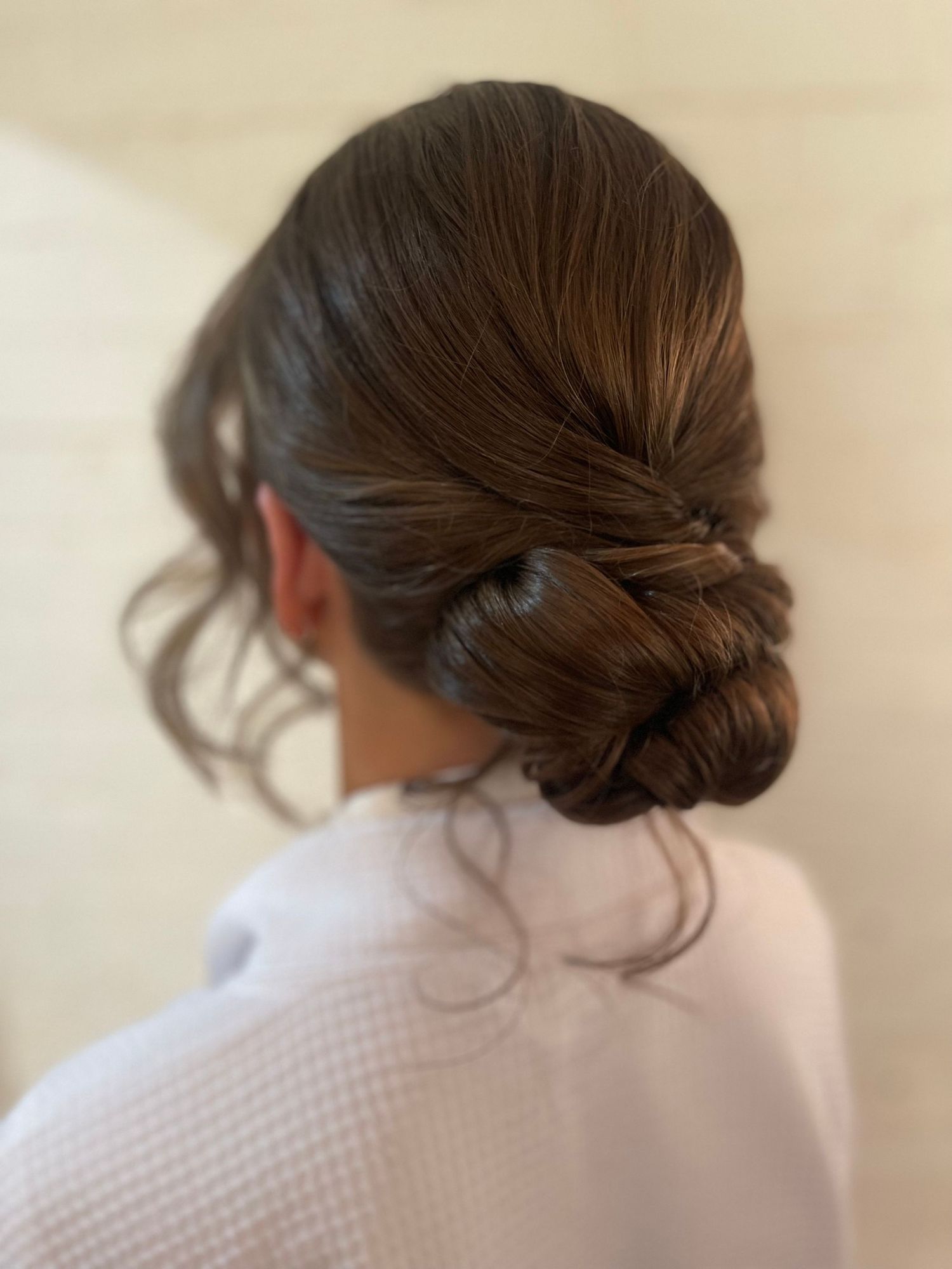 Thick long brunette hair twisted into a low bun pinned neatly with soft face framing
