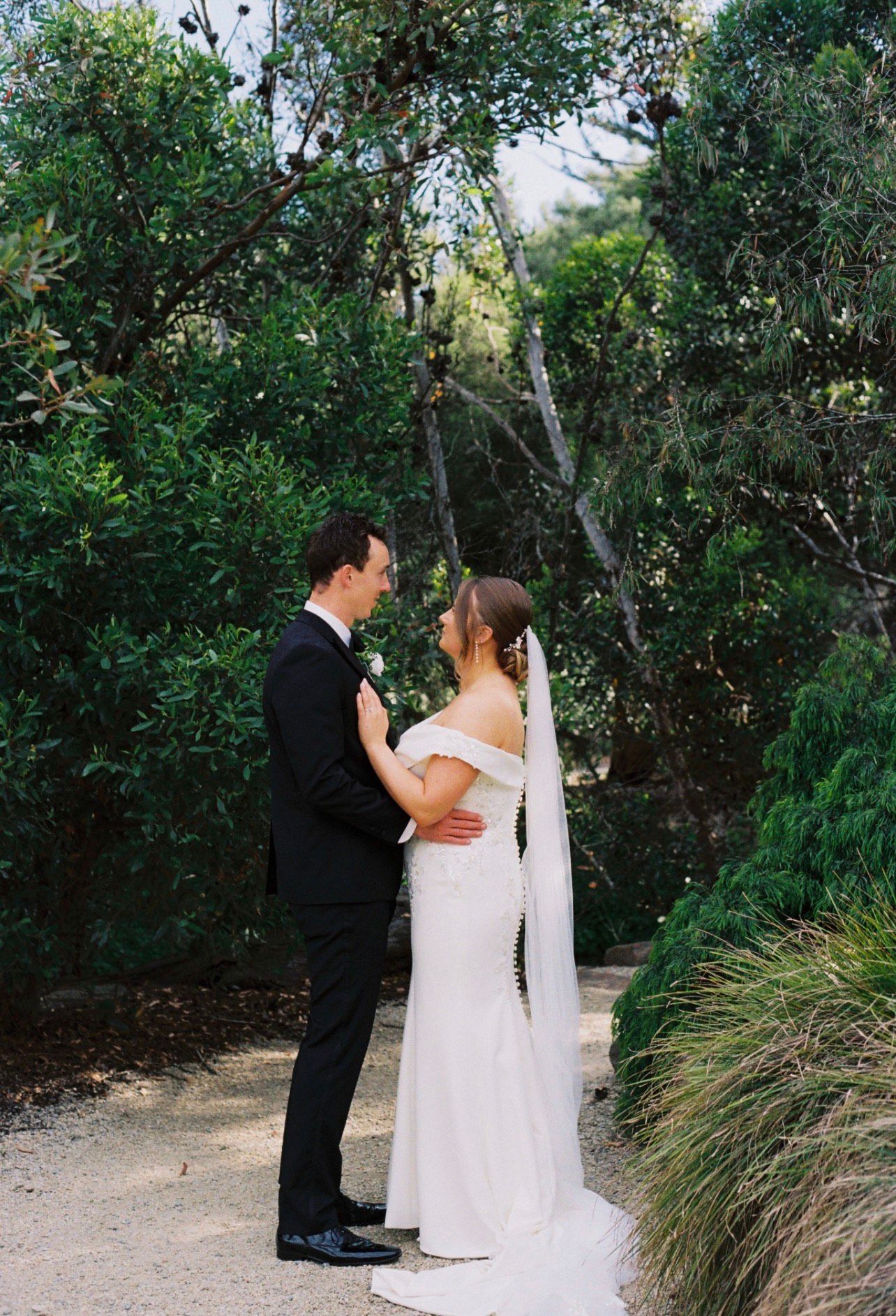 Beach wedding low structured bridal hair with soft face framing and a flowing veil.bridal hair is medium length and thick brunette