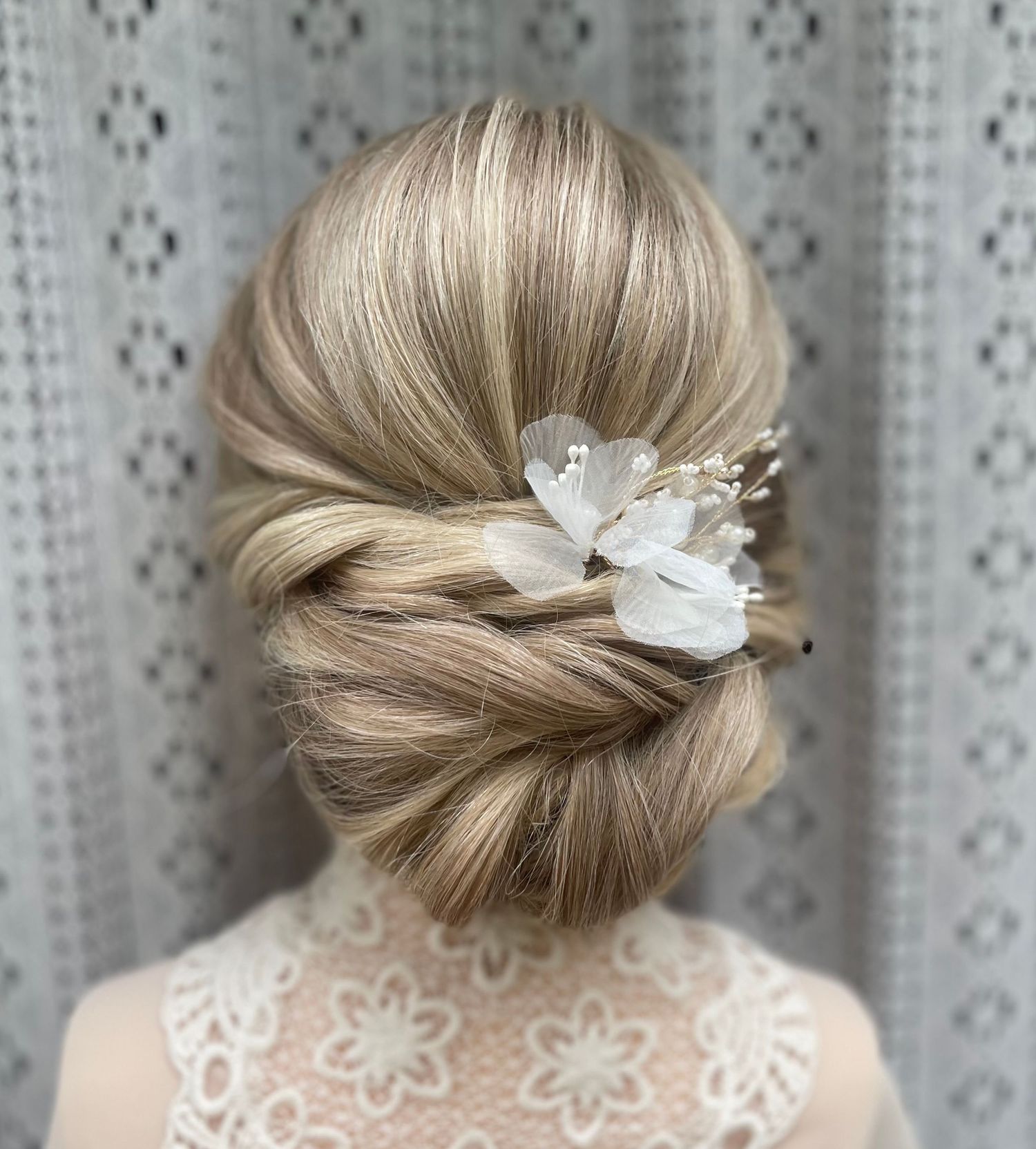 Thick long hair twisted into an elegant low bun detailed with a floral accessory