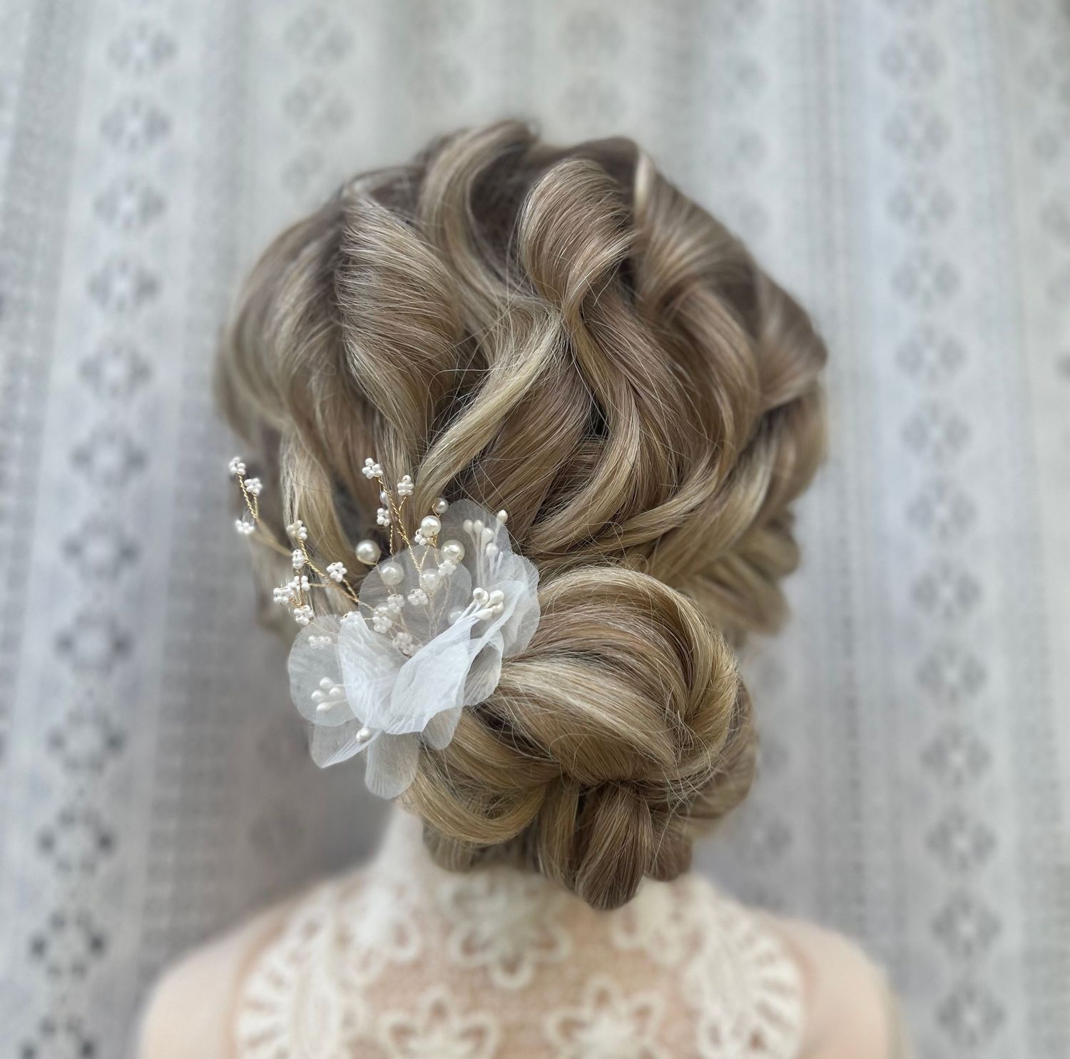 Textured low bun twisted curls for a boho chic look finished off with a flower accessory