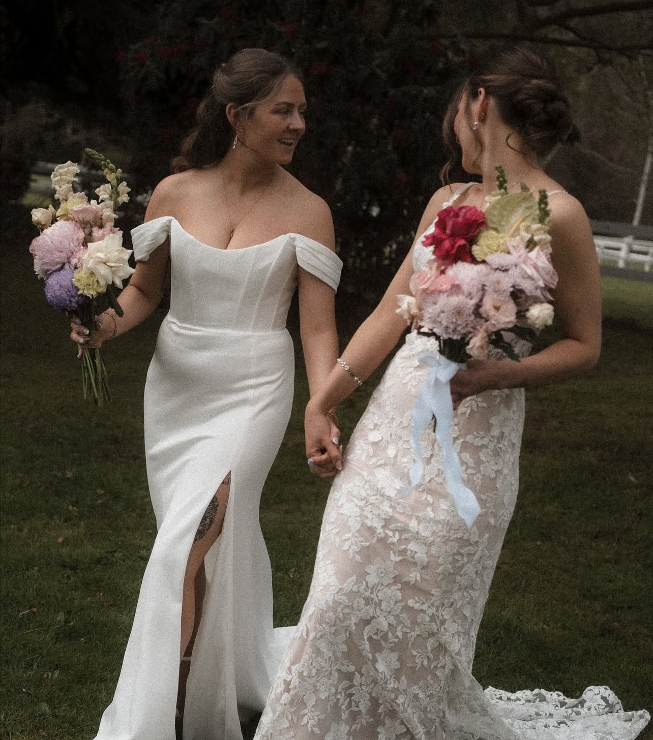 Brides one with a fluffy textured curl half up half down the other wit a curled textured low bun both with bright coloured bouquets