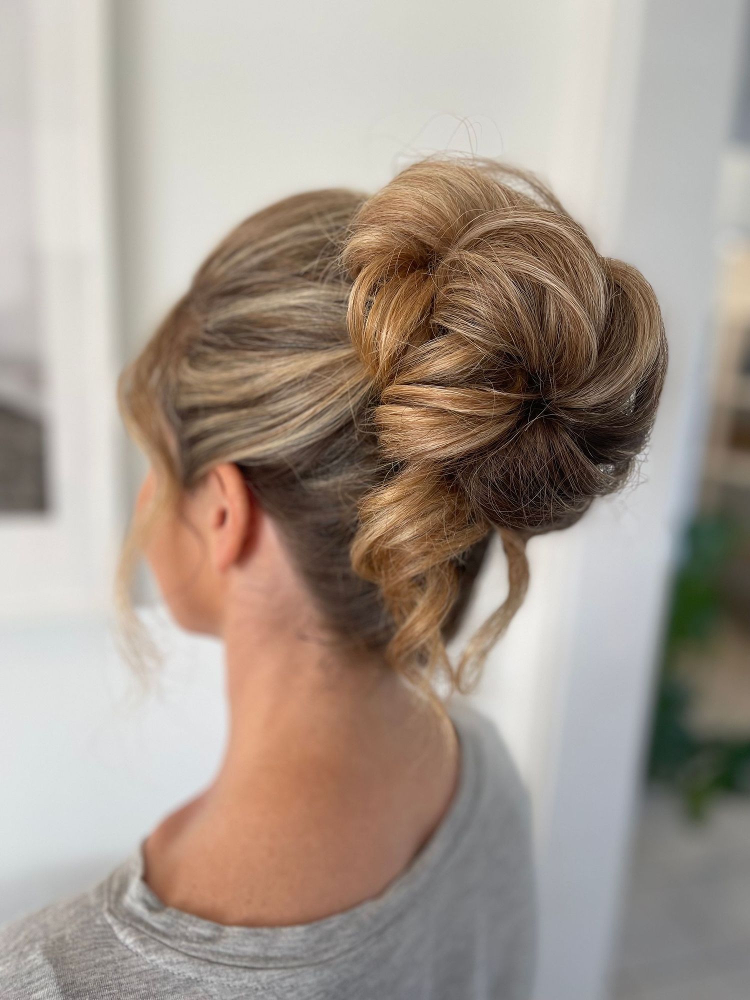 Loose curl twisted bridal high bun with thick hair creating volume and texture for a softer finish