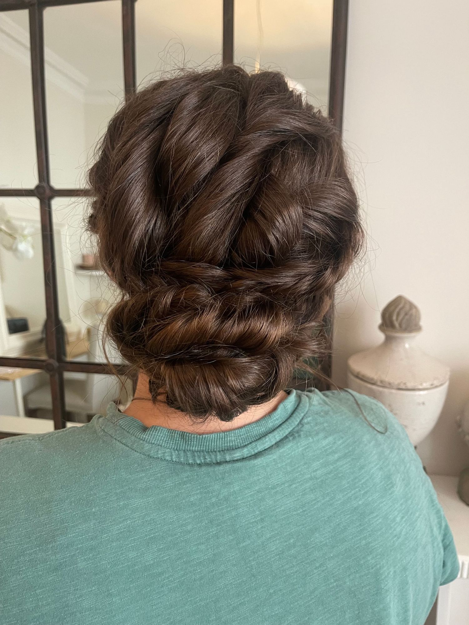 Long brunette hair twisted to give texture and volume into a low bun at the bottom
