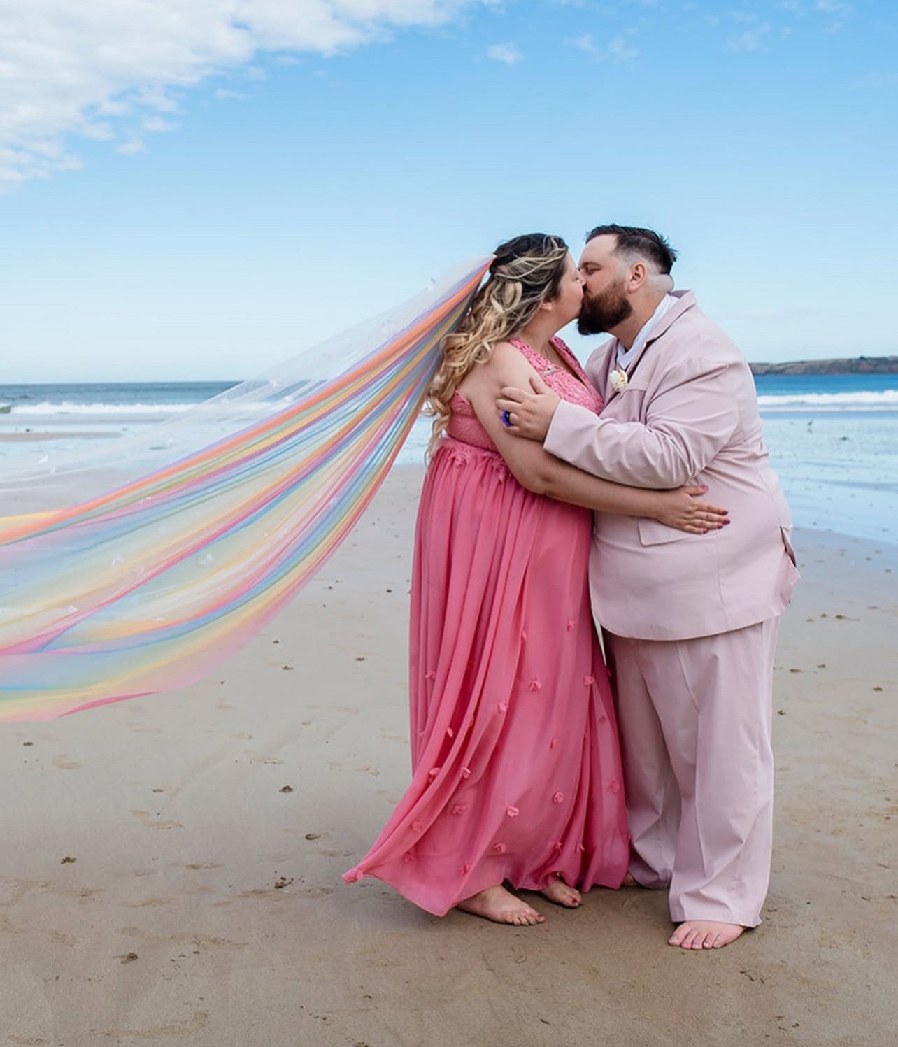 Rainbow wedding on the beach the brides hair is big curls twisted into half up half down using long blonde hair extensions