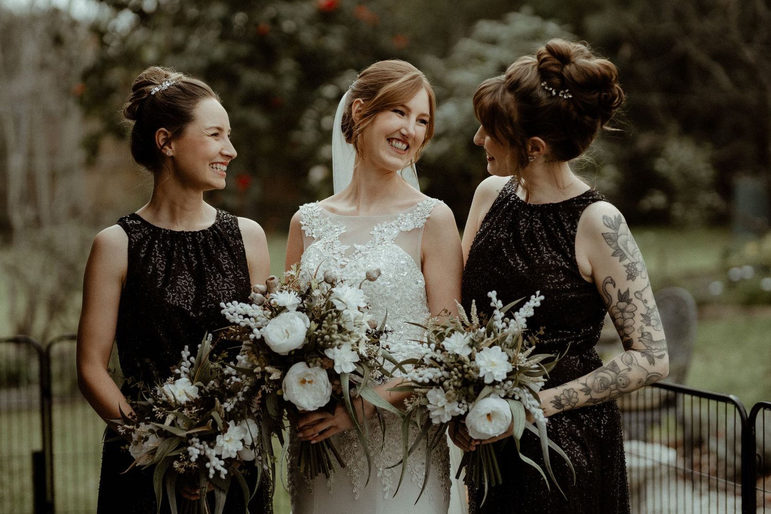 Brunette high soft curled buns. Redhead neat low bun with face framing. Elegant hair styling with veil. Garden wedding.