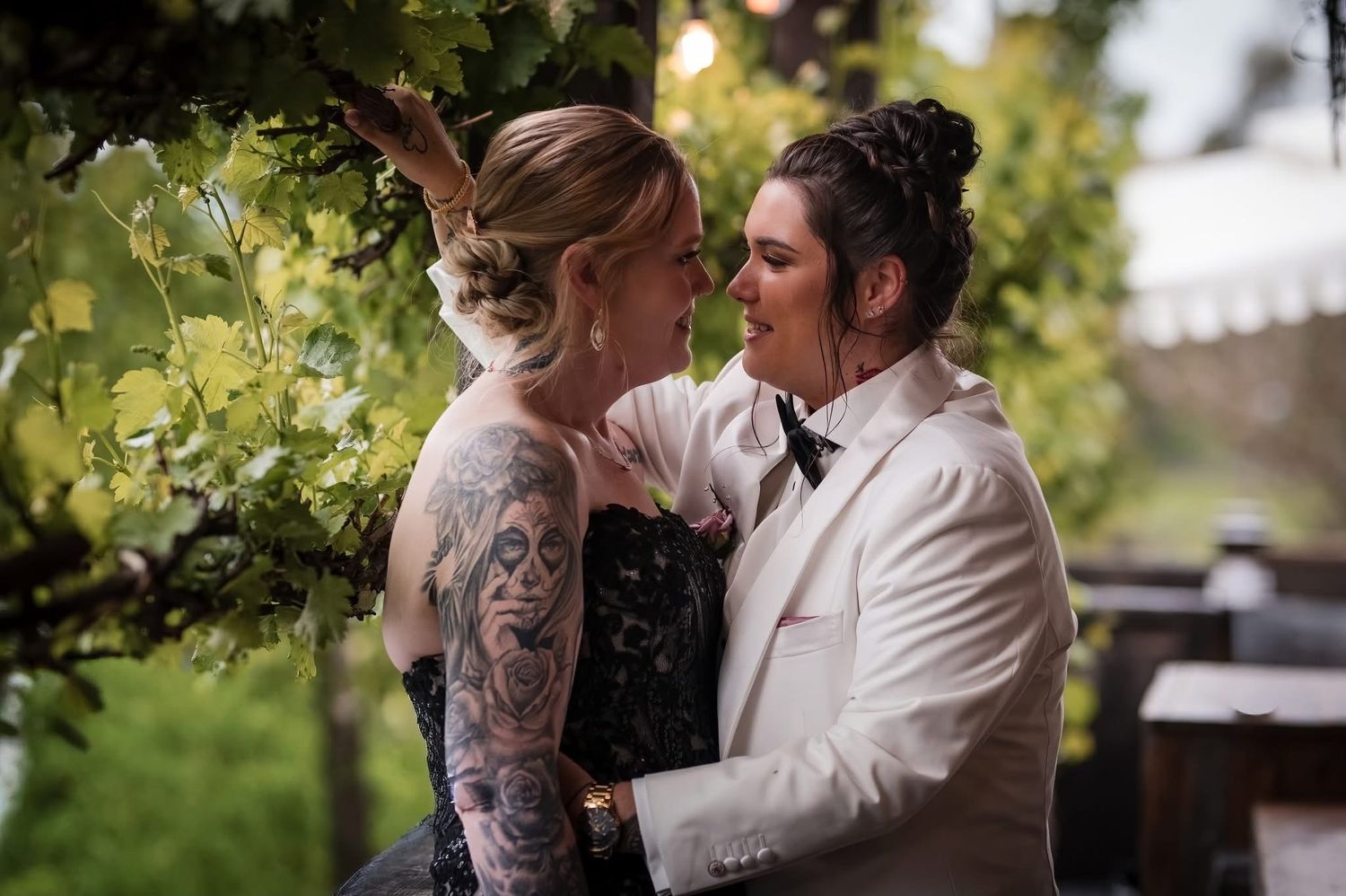 Same sex wedding with two brides ones with a low messy bun pinned back and one bride with a high messy bun and soft face framing