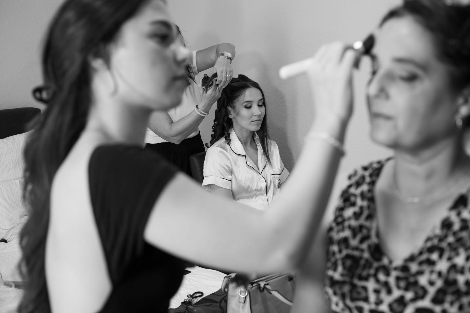 Professional makeup artist applies cosmetics during bridal preparation in black and white photography.
