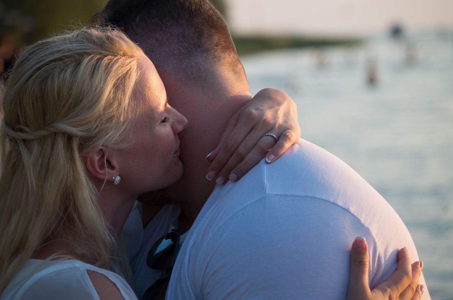 Silhouettes of a couple embracing against a sunset ocean backdrop.