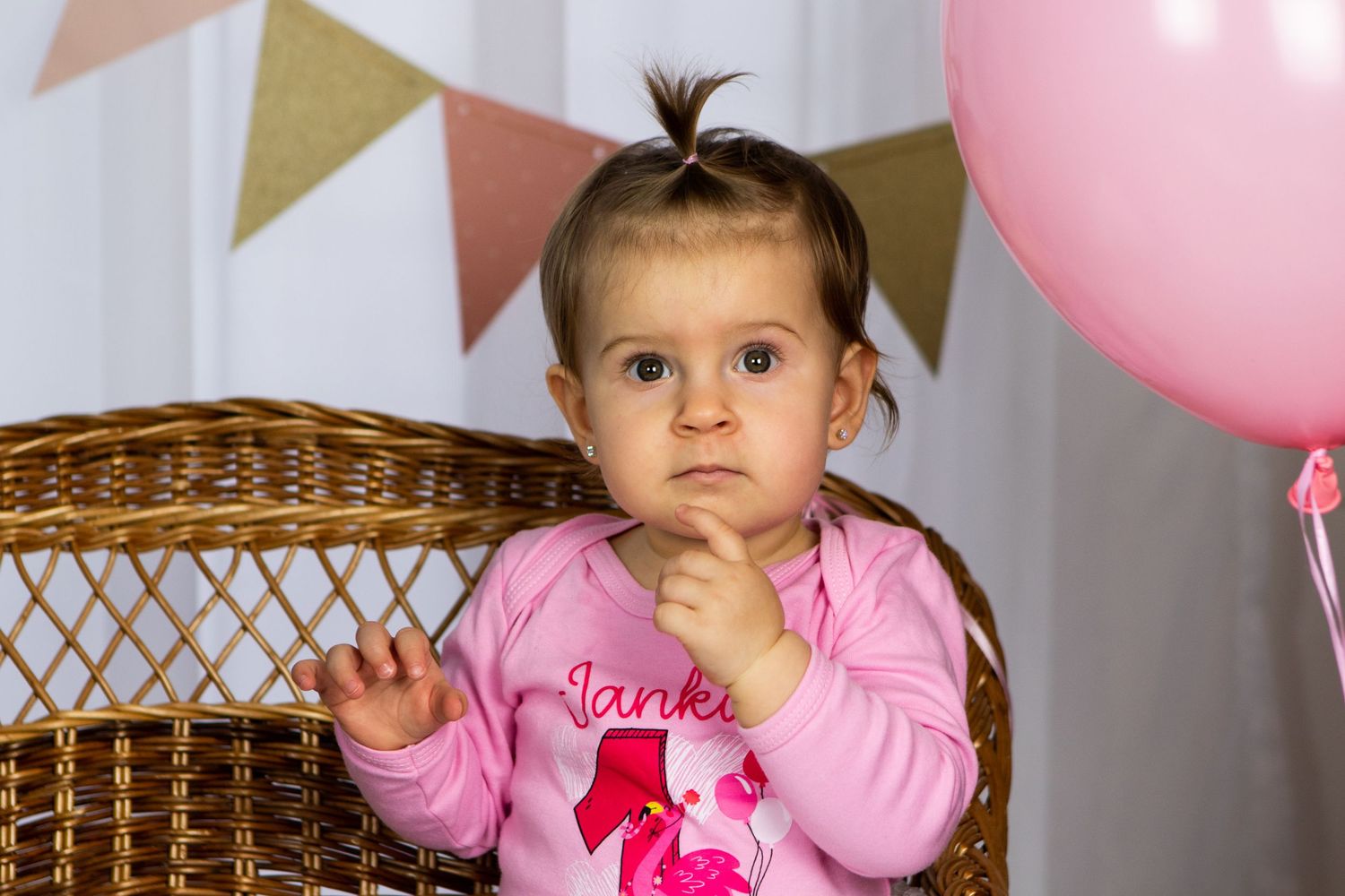 Birthday celebration setup with pink and blue balloons against white backdrop.