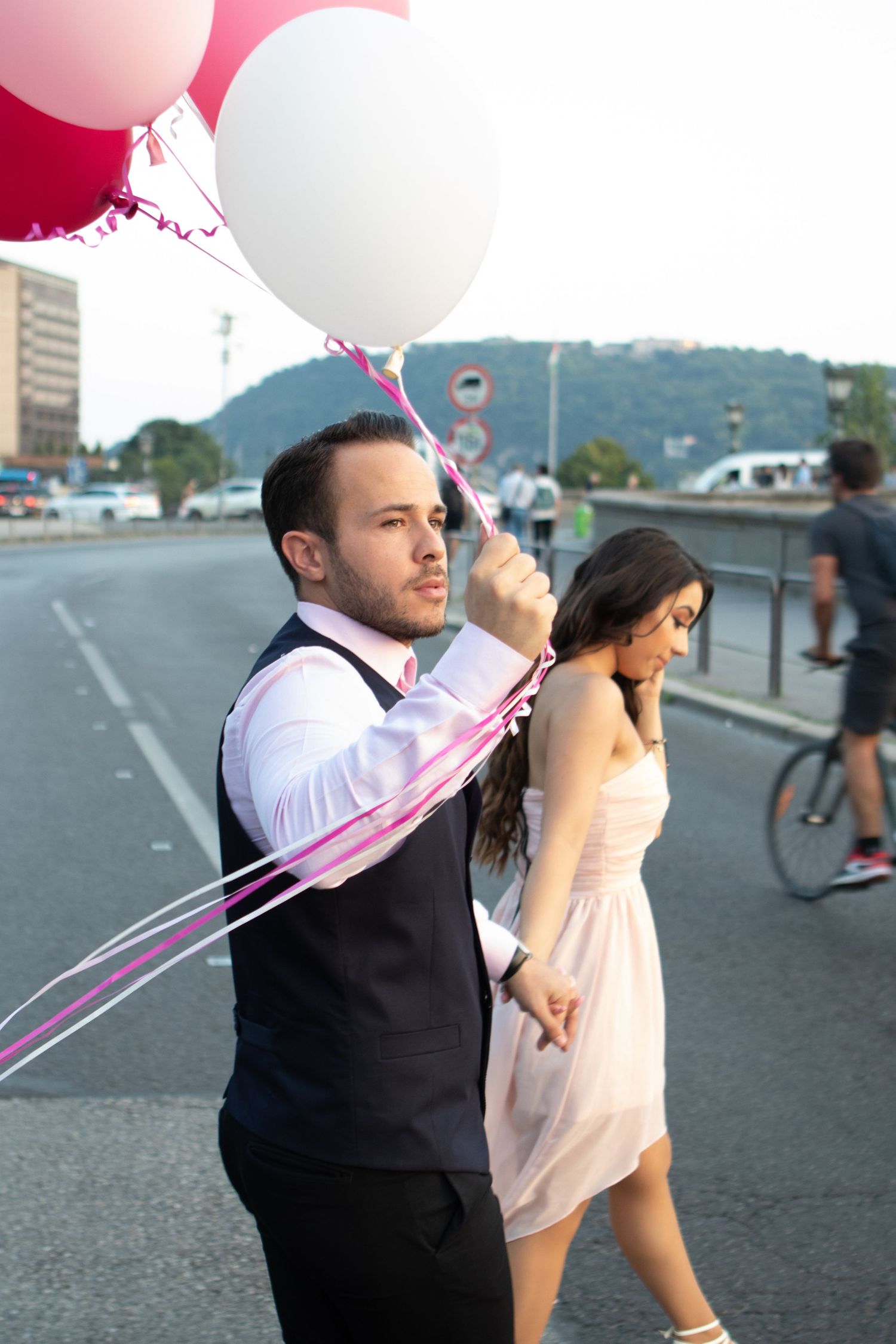 Couple walking on street with red and white balloons during outdoor celebration.
