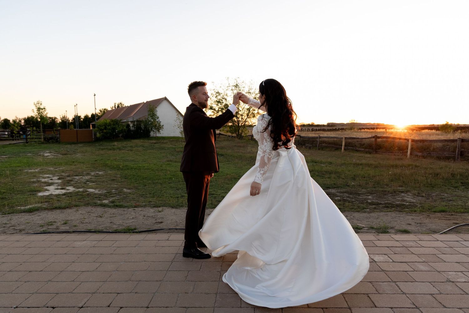 A couple dances together at sunset on their wedding day with a flowing white dress.