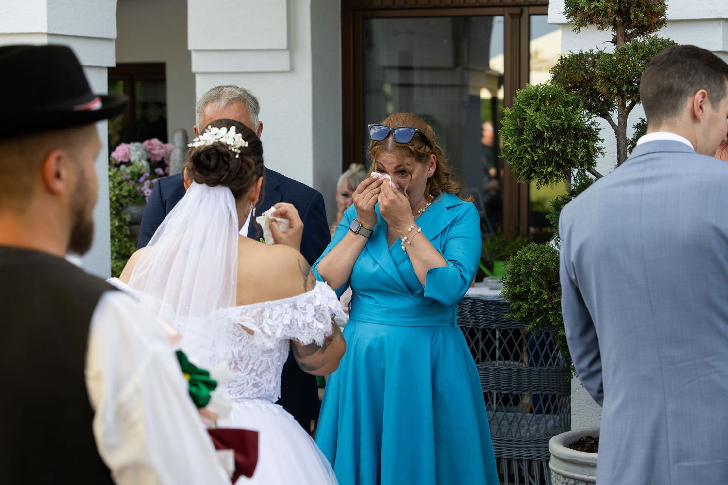 Wedding guests mingling outside a white columned building during a reception.
