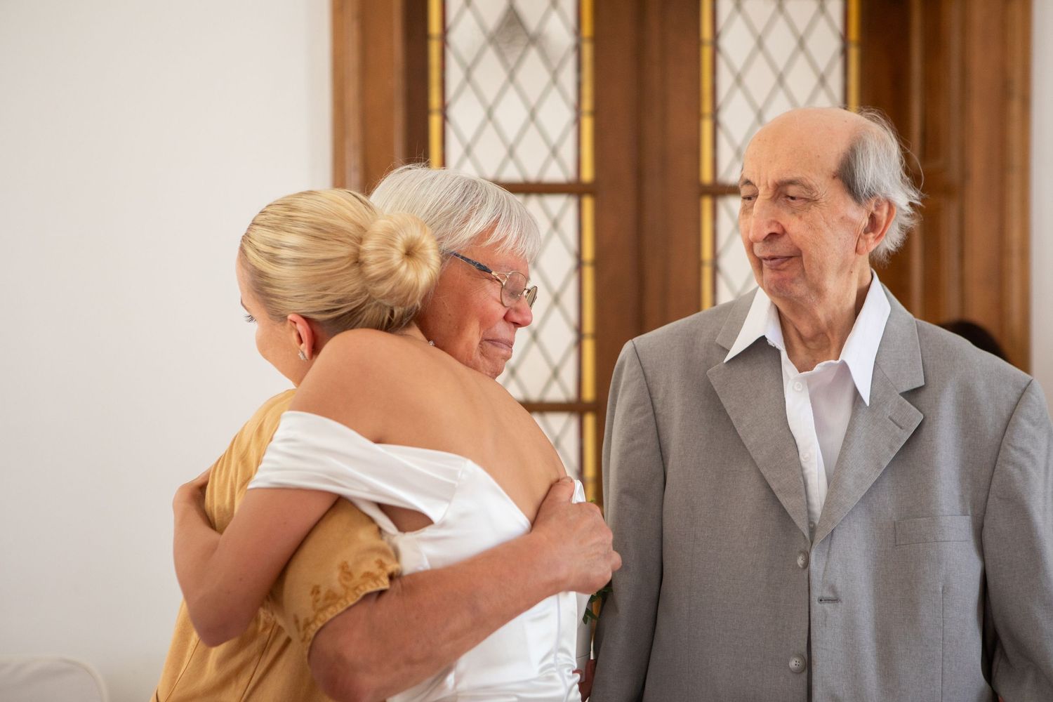 Wedding party posing in front of a classic church interior with diamond-paned windows.
