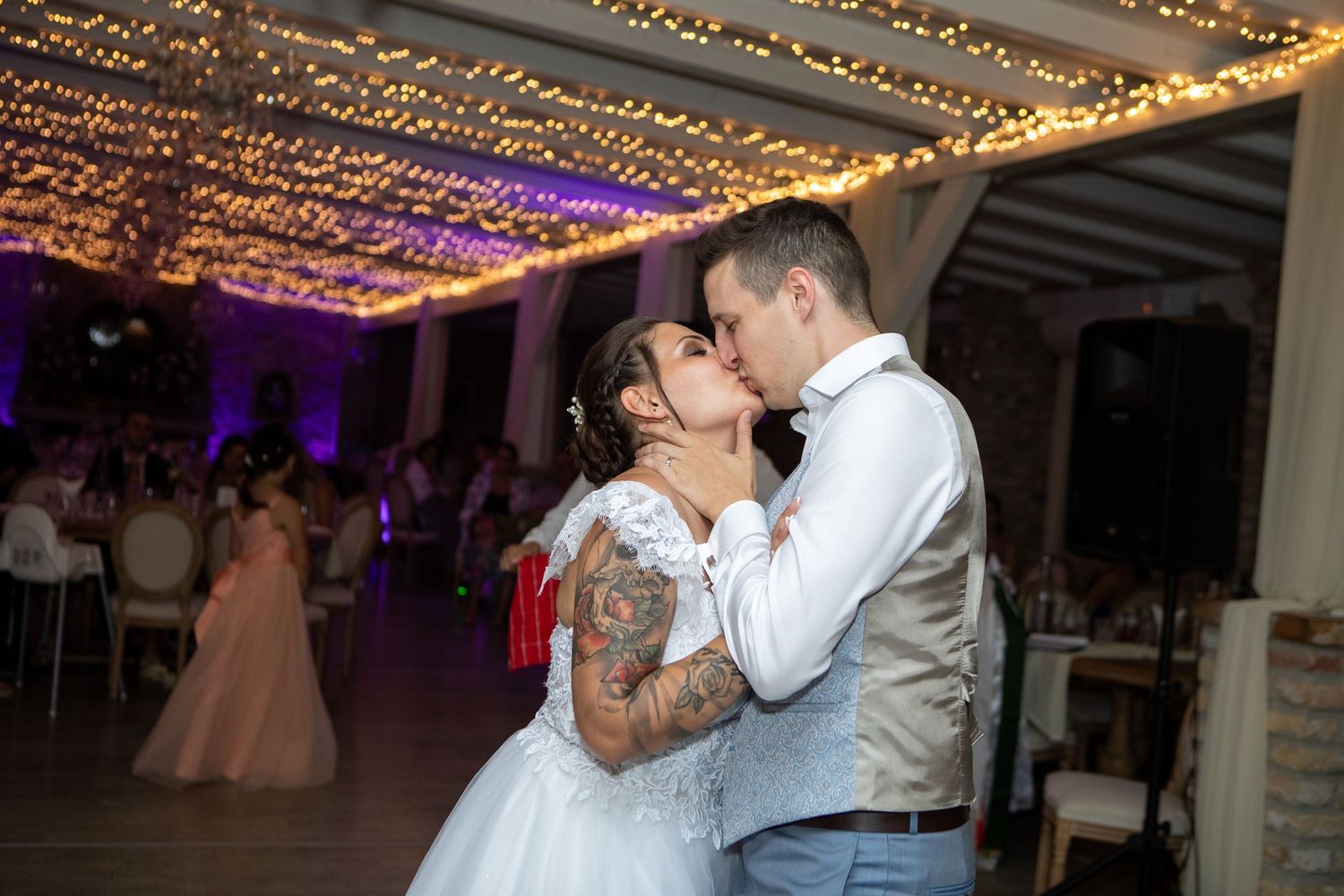 Couple shares romantic dance under twinkling lights at wedding reception.