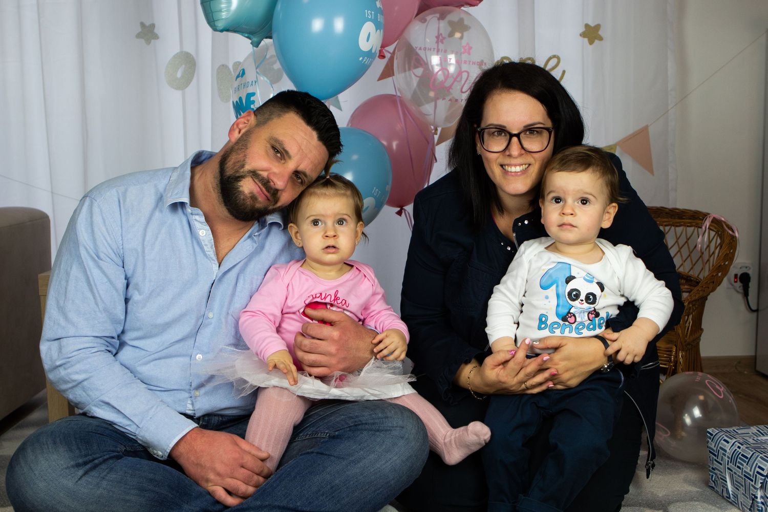 Family portrait session with balloons and decorative banner backdrop.