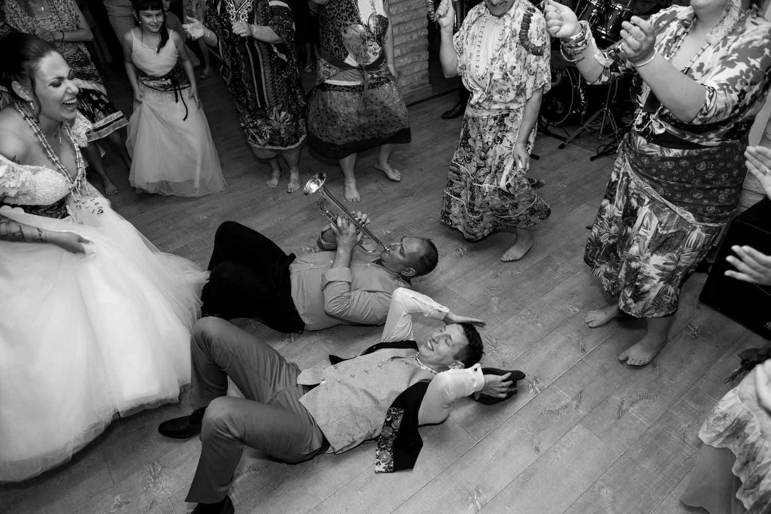 Black and white photo of wedding guests dancing on wooden floor during reception.
