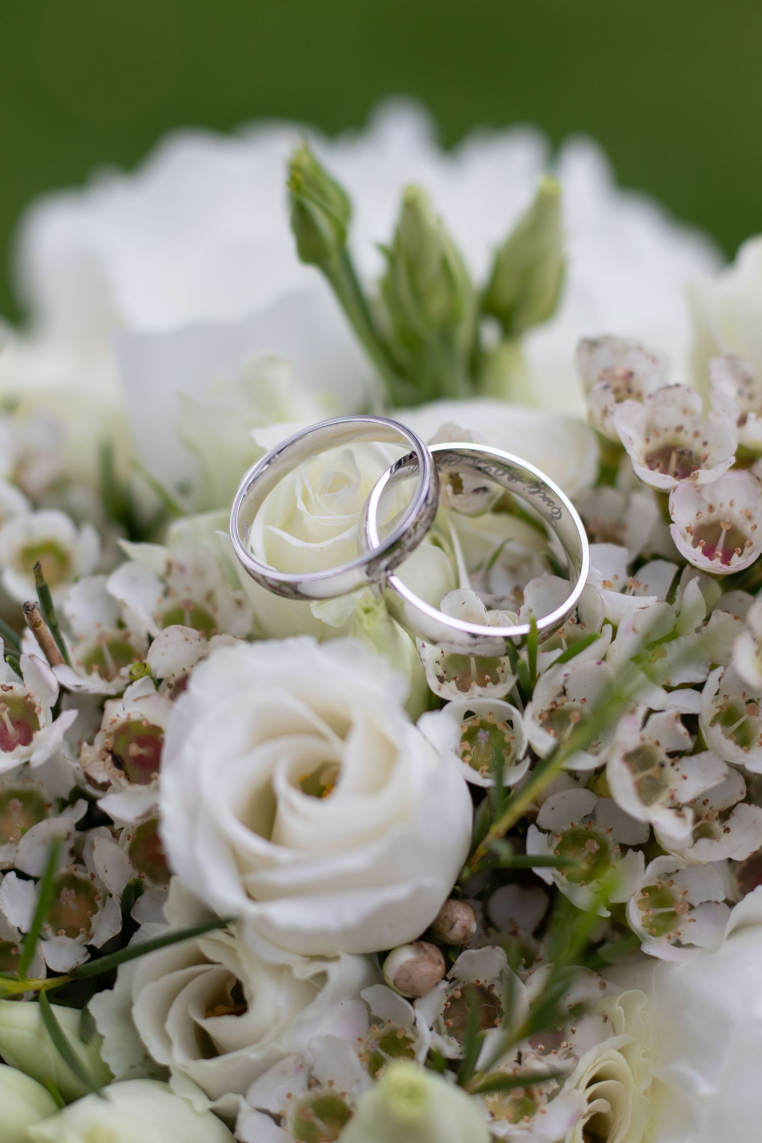 Wedding rings nestled among white roses and delicate flowers.