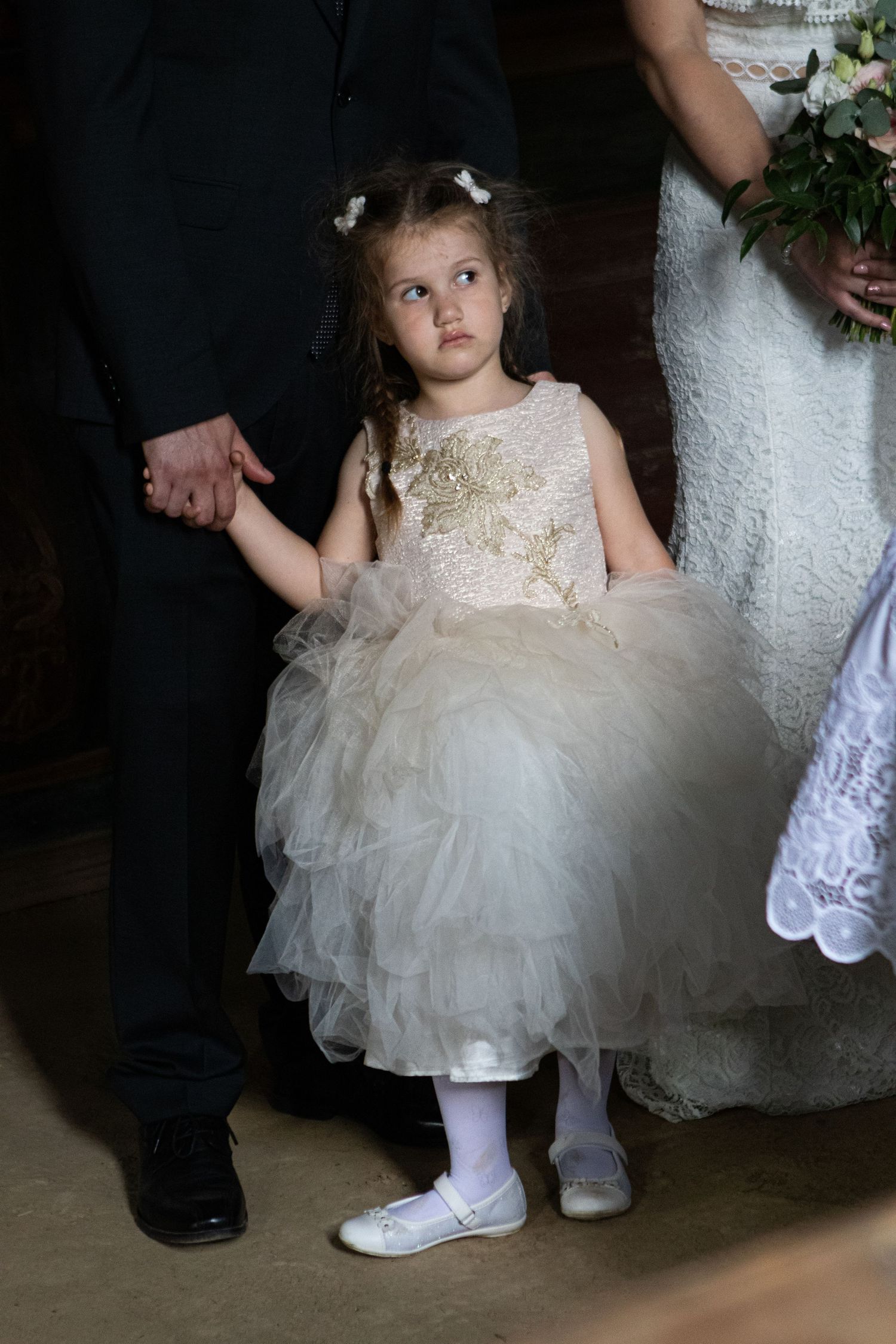 Sweet flower girl in a cream tulle dress stands beside wedding party.