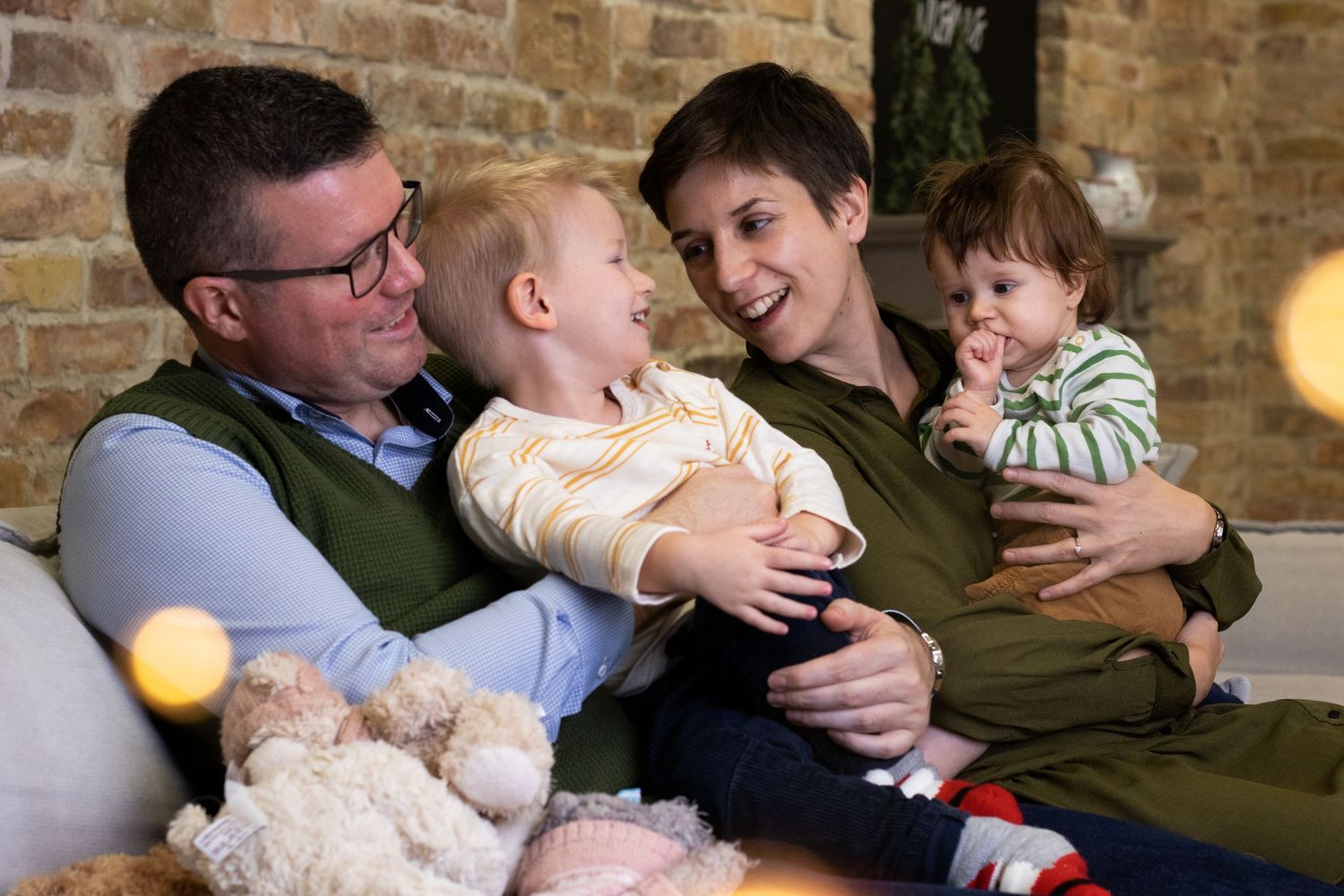 Family lifestyle session with multiple candid moments against brick wall.