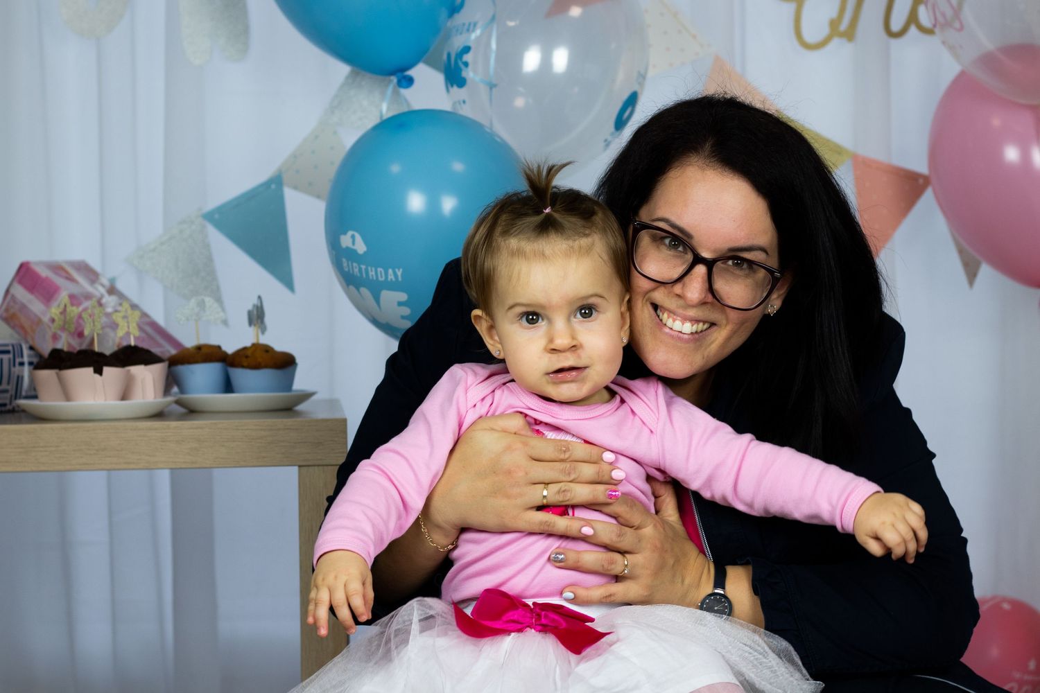 Celebration scene with pink and blue balloons decorating a white backdrop.