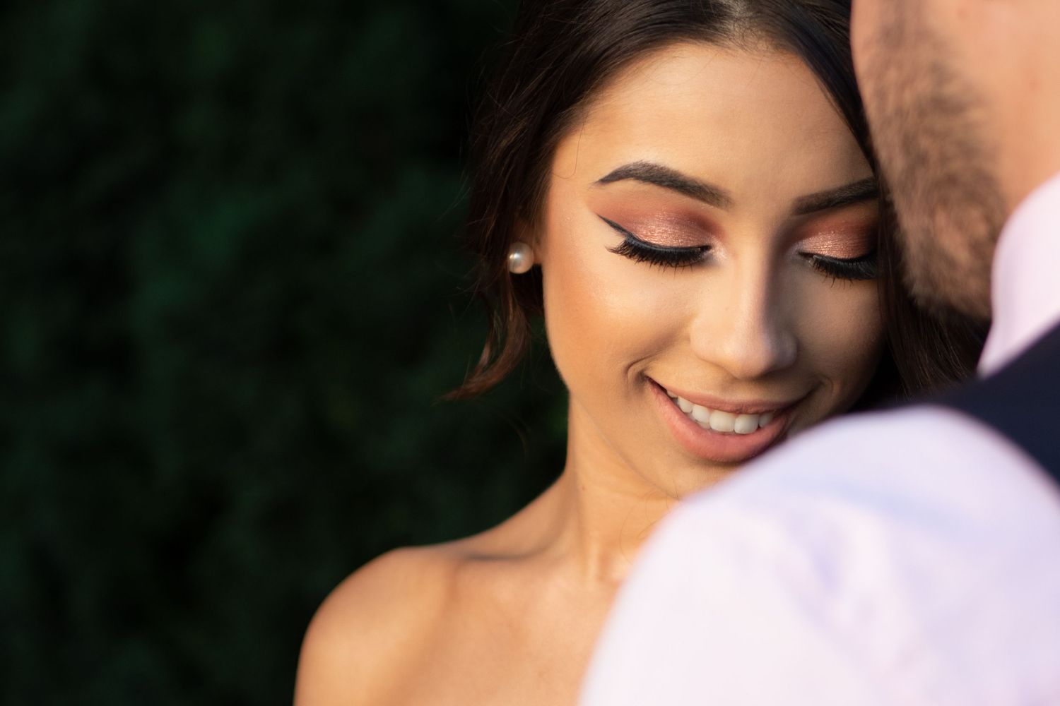 Close up beauty shot of woman with closed eyes and glowing makeup in romantic setting.