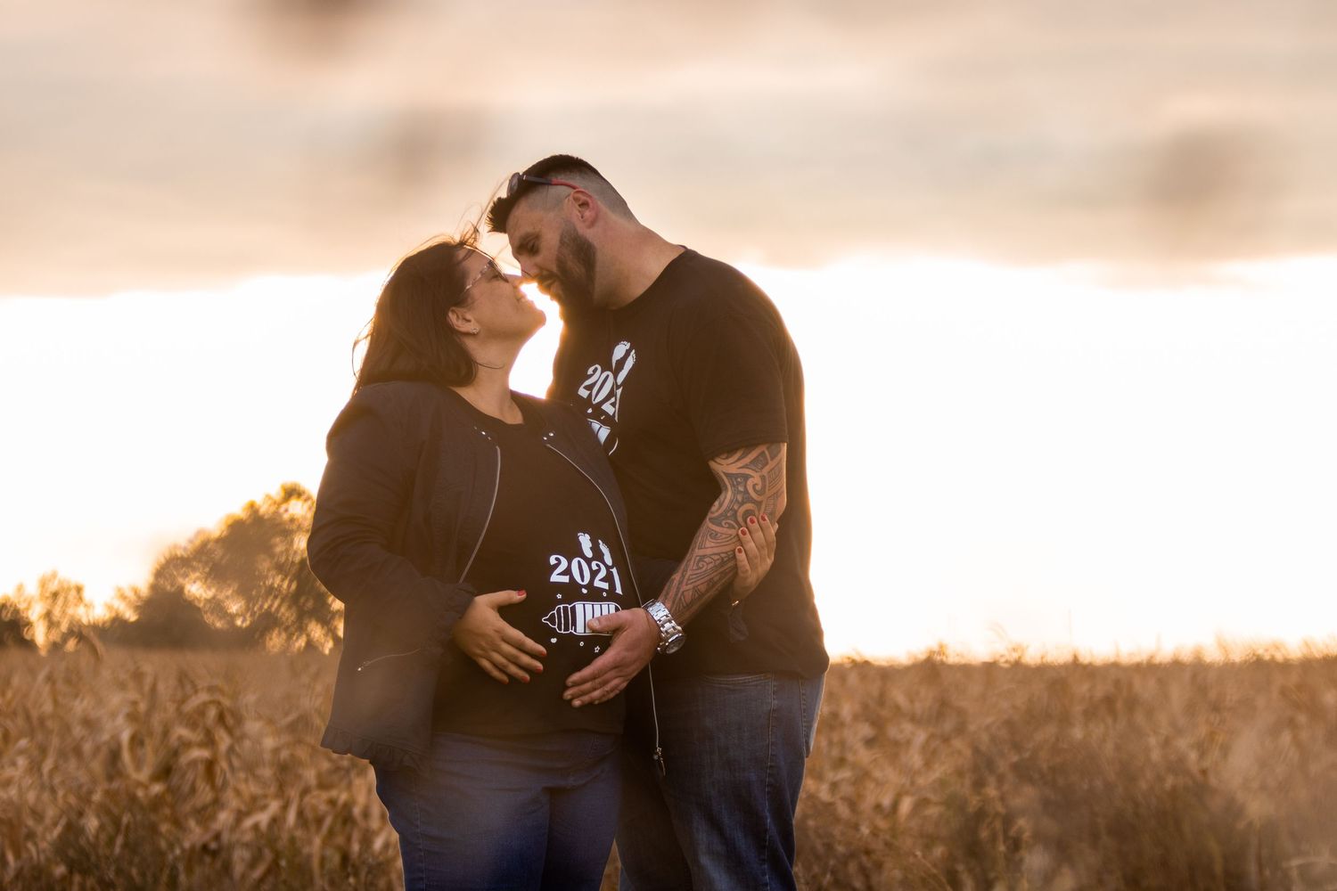 Romantic sunset photoshoot in a golden wheat field with warm lighting.