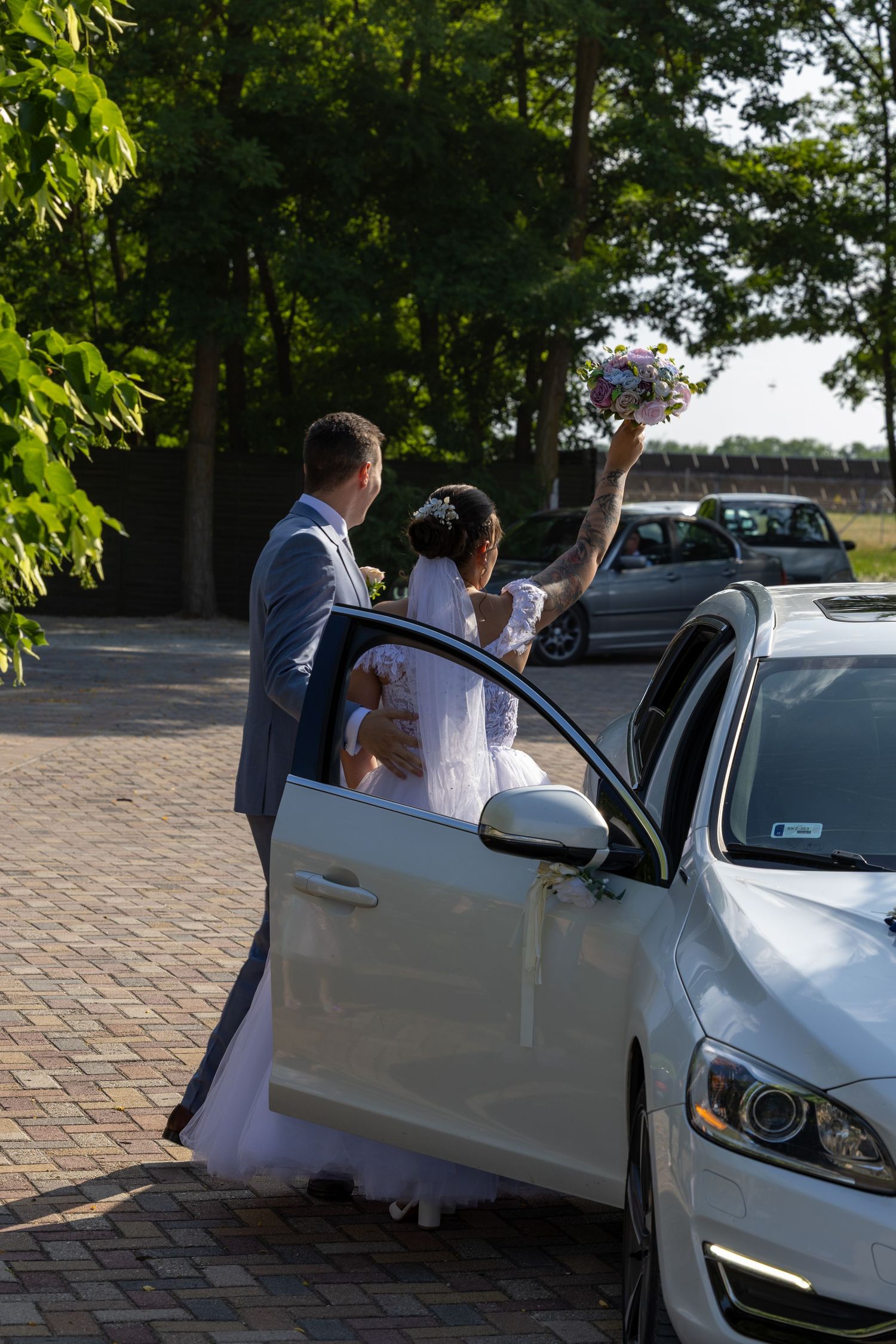 A couple getting into a white car after their wedding ceremony.