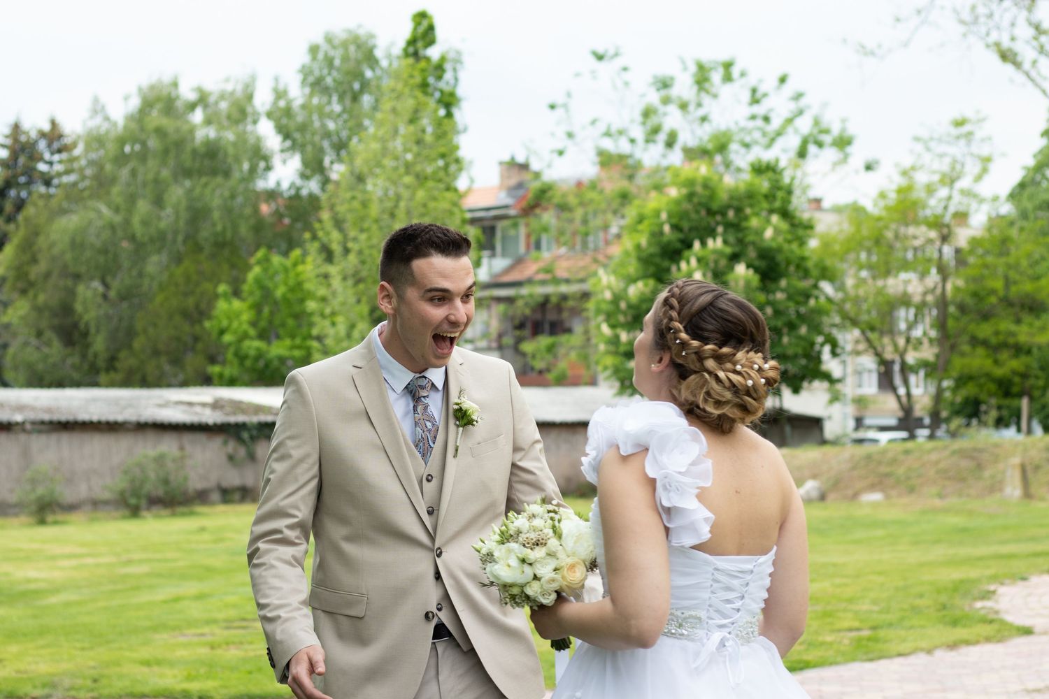 Wedding couple walking together on a path surrounded by spring greenery.