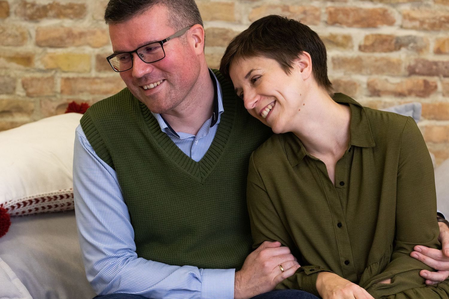Candid indoor portrait session against exposed brick wall background.
