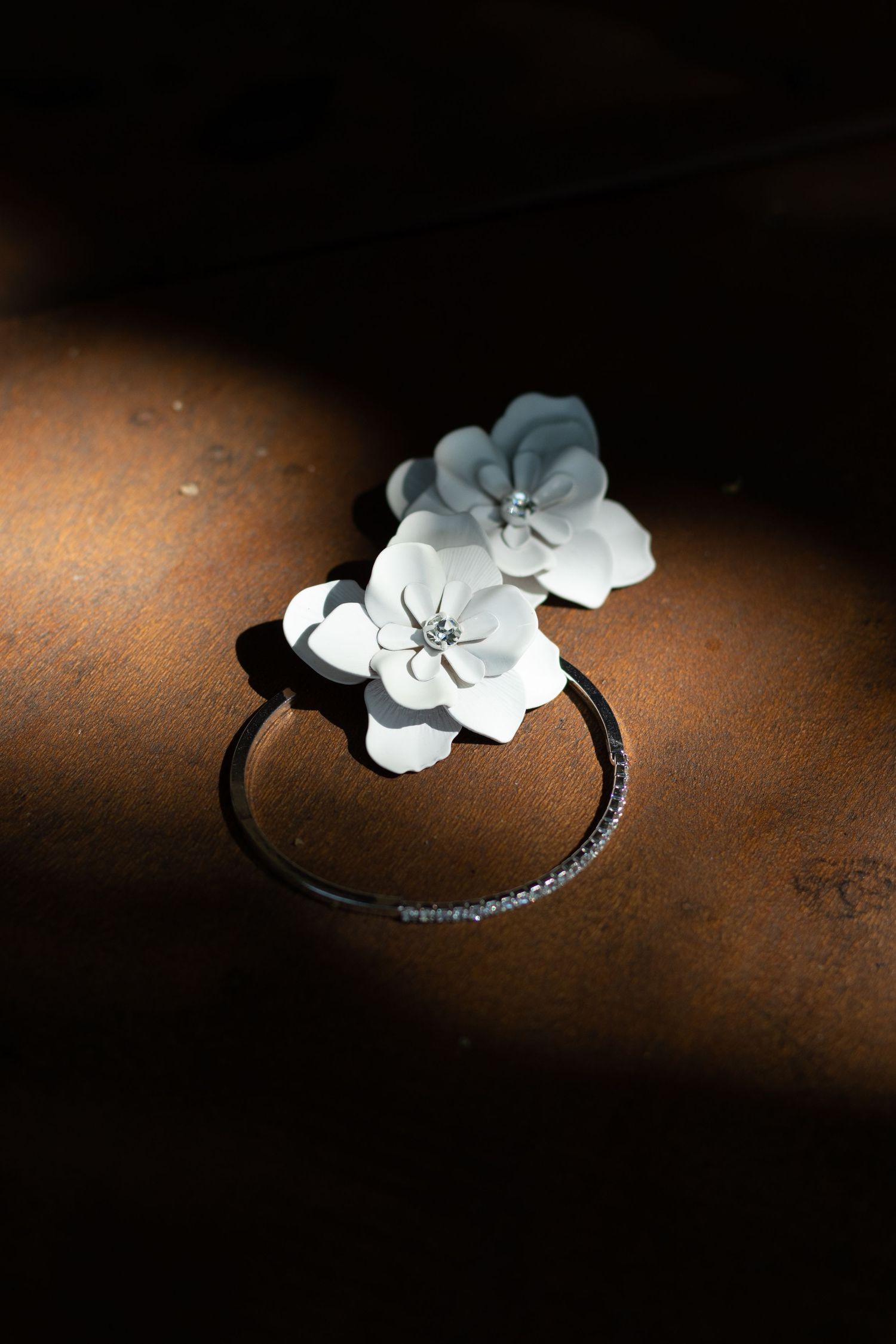 White floral hair accessory on dark textured surface in dramatic lighting.