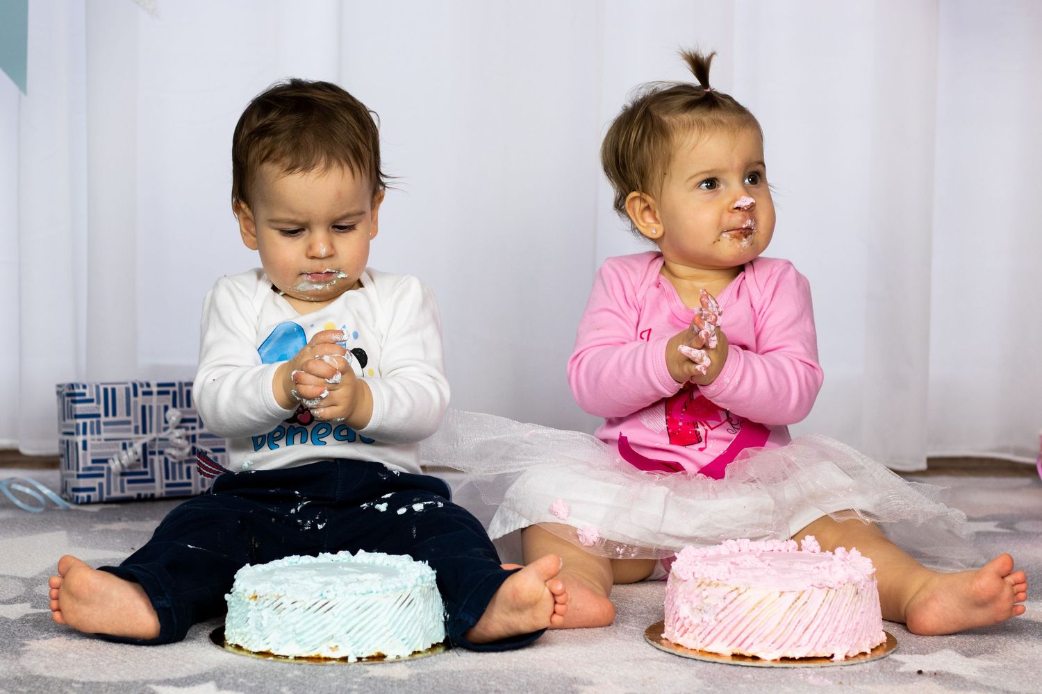 Multiple shots of babies exploring birthday cakes on white background with decorative elements.