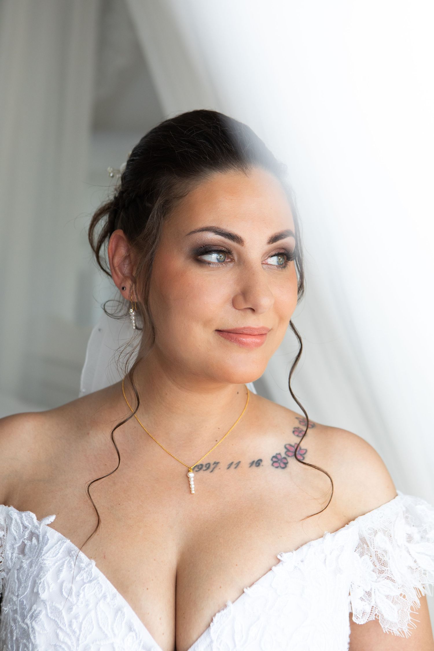 Elegant bridal portrait featuring lace off-shoulder dress and delicate jewelry.